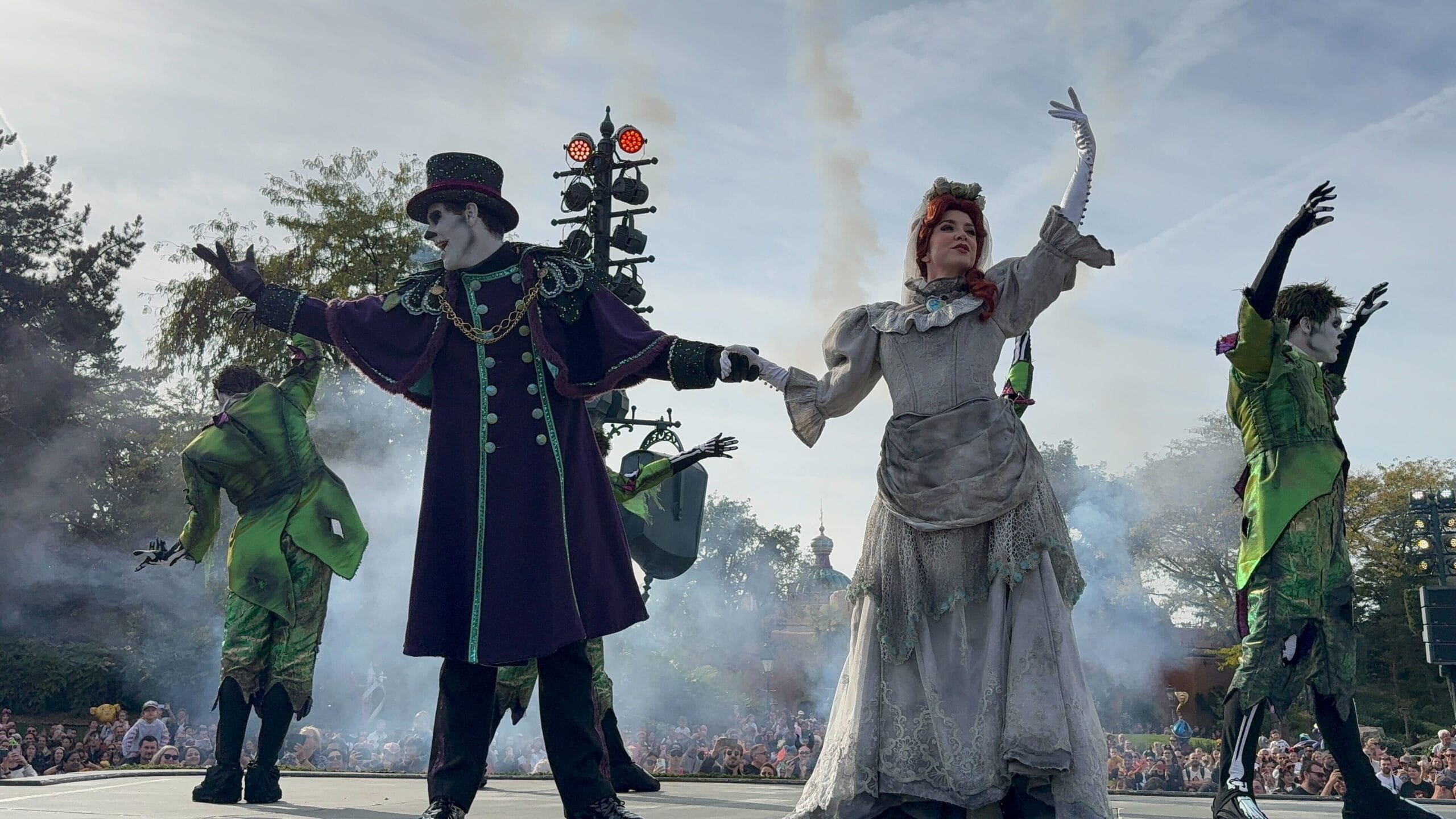 Two people in spooky costumes perform onstage amid smoke at Disneyland Paris’s 2025 Mickey’s Halloween Celebration Parade.