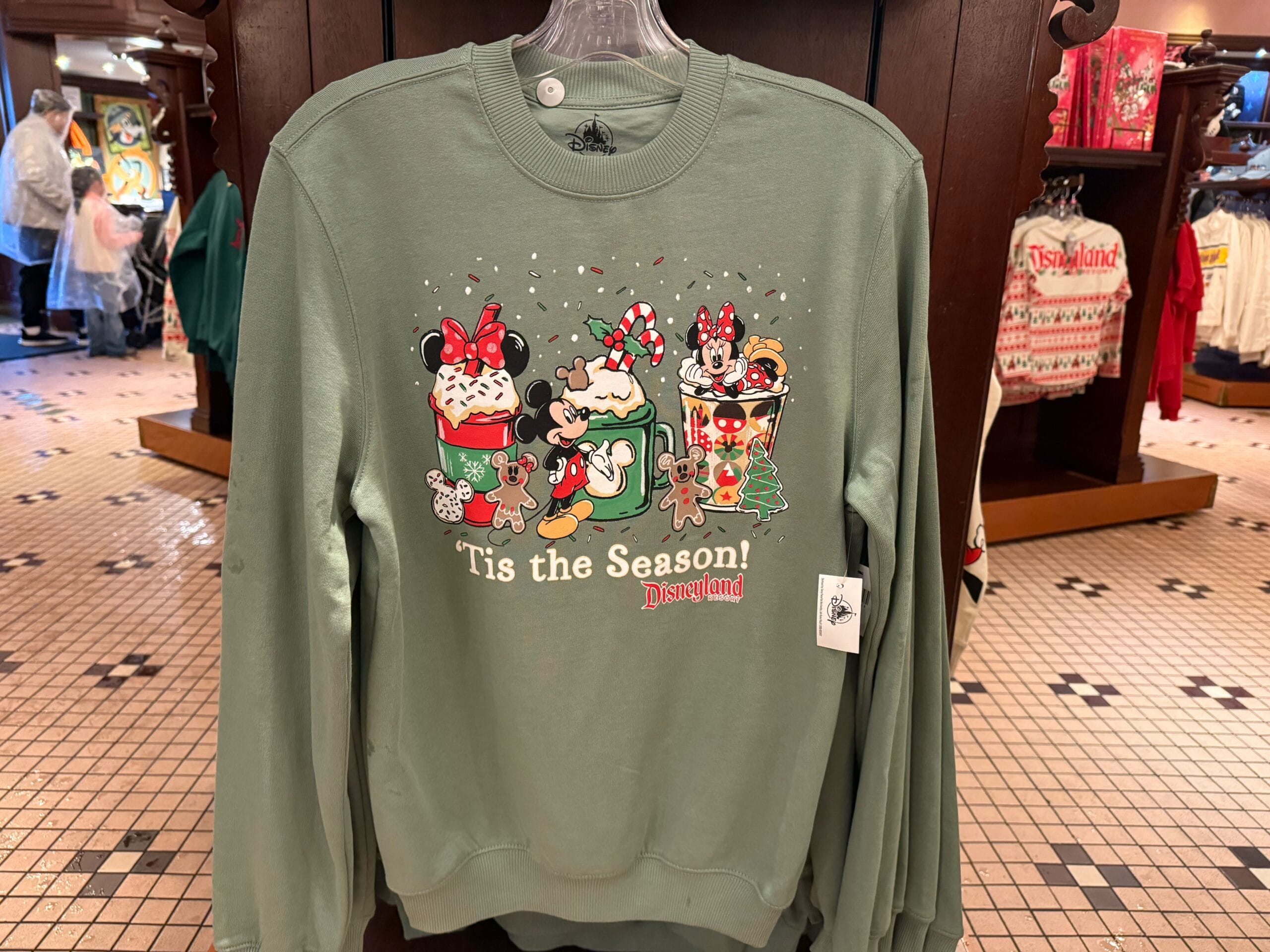 Green Disneyland Christmas sweatshirt features Mickey, Minnie, and Pluto in festive 2025 outfits, perfect for park holiday celebrations.
