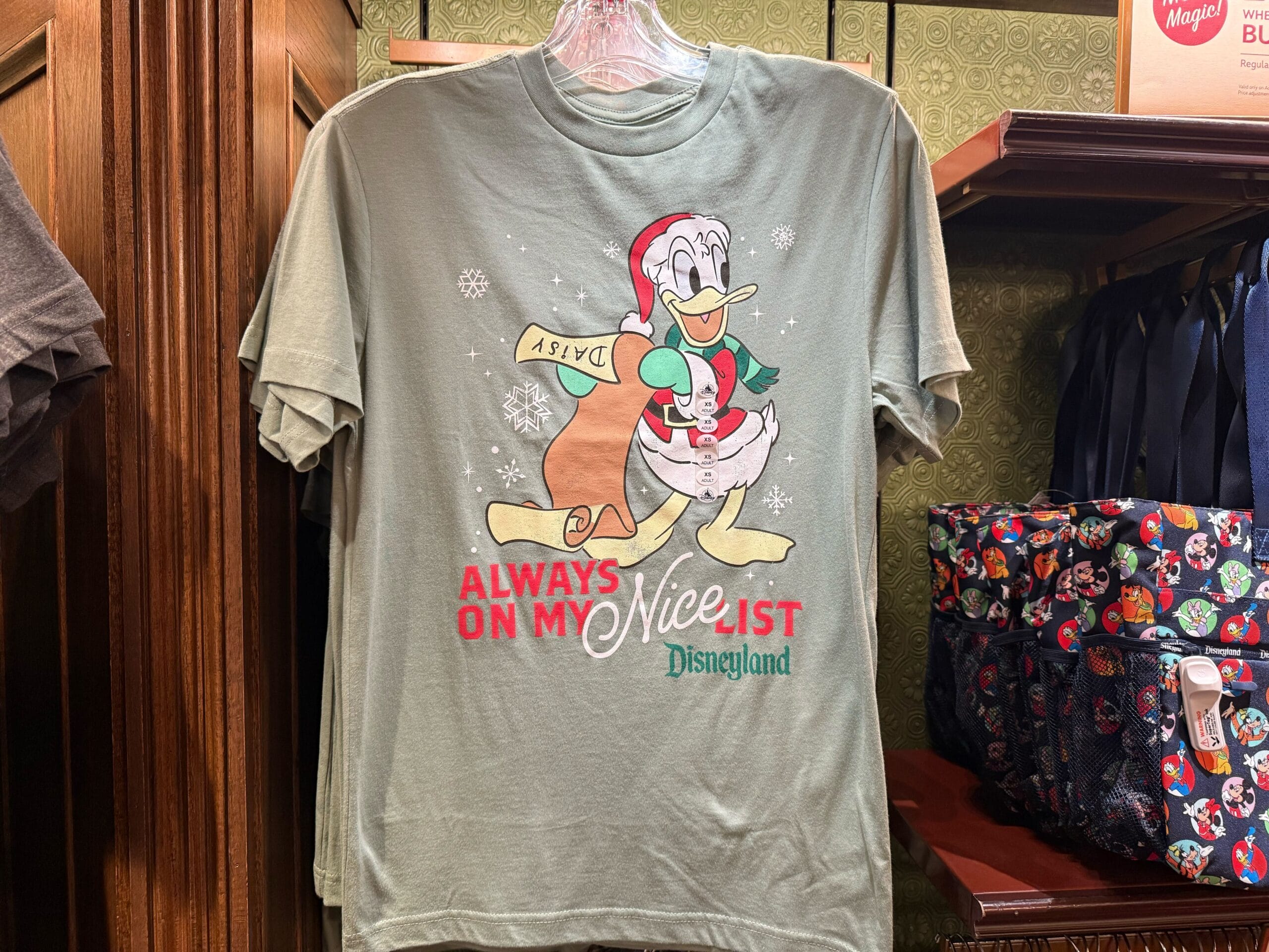 A green tee featuring Donald Duck in a Santa suit, from Disneyland’s 2025 Christmas line—merch found across Disney Parks globally.