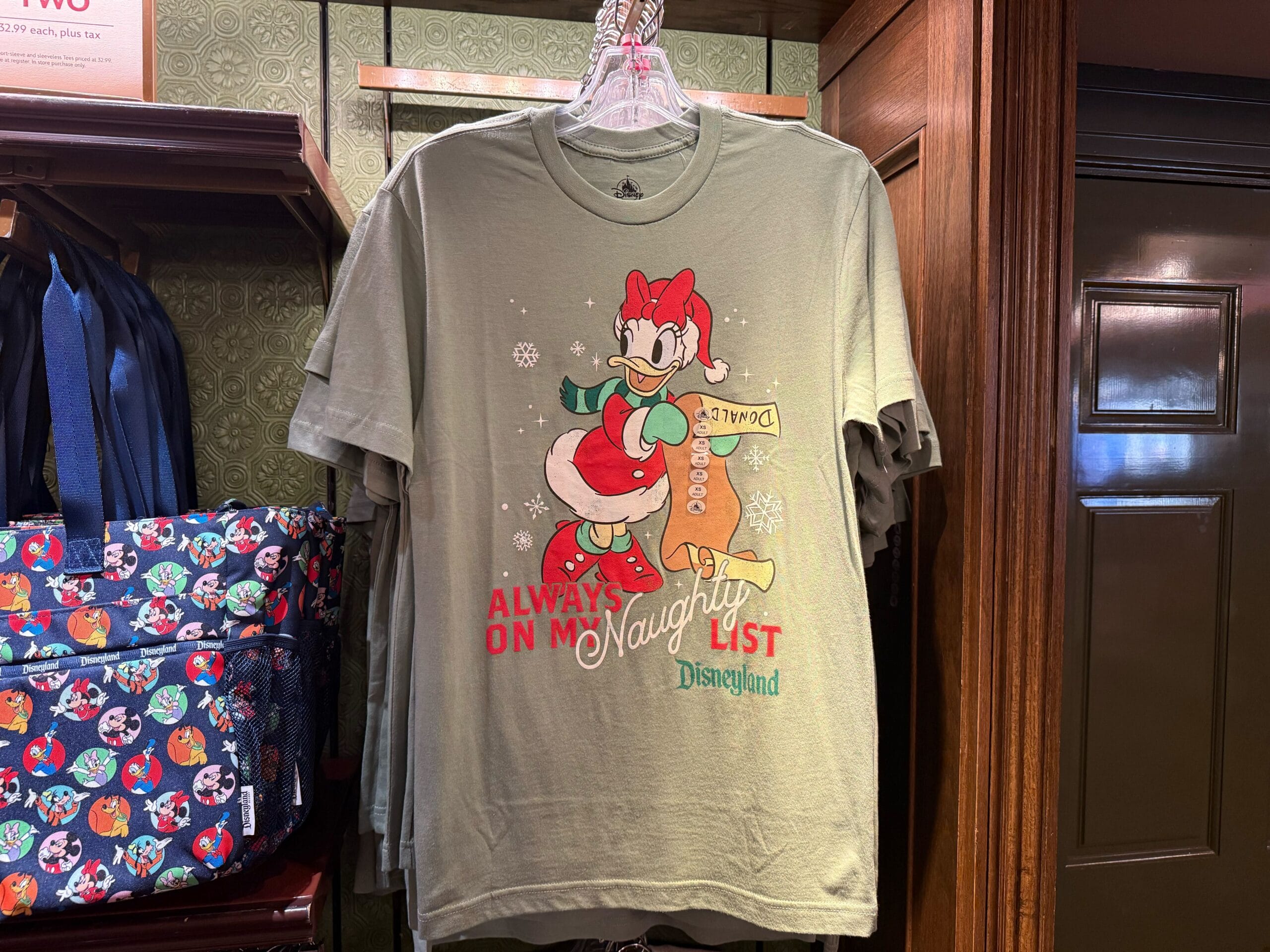 A green Christmas Holiday Shirt featuring Daisy Duck in a Santa outfit and "Always on the Naughty List. Disneyland.