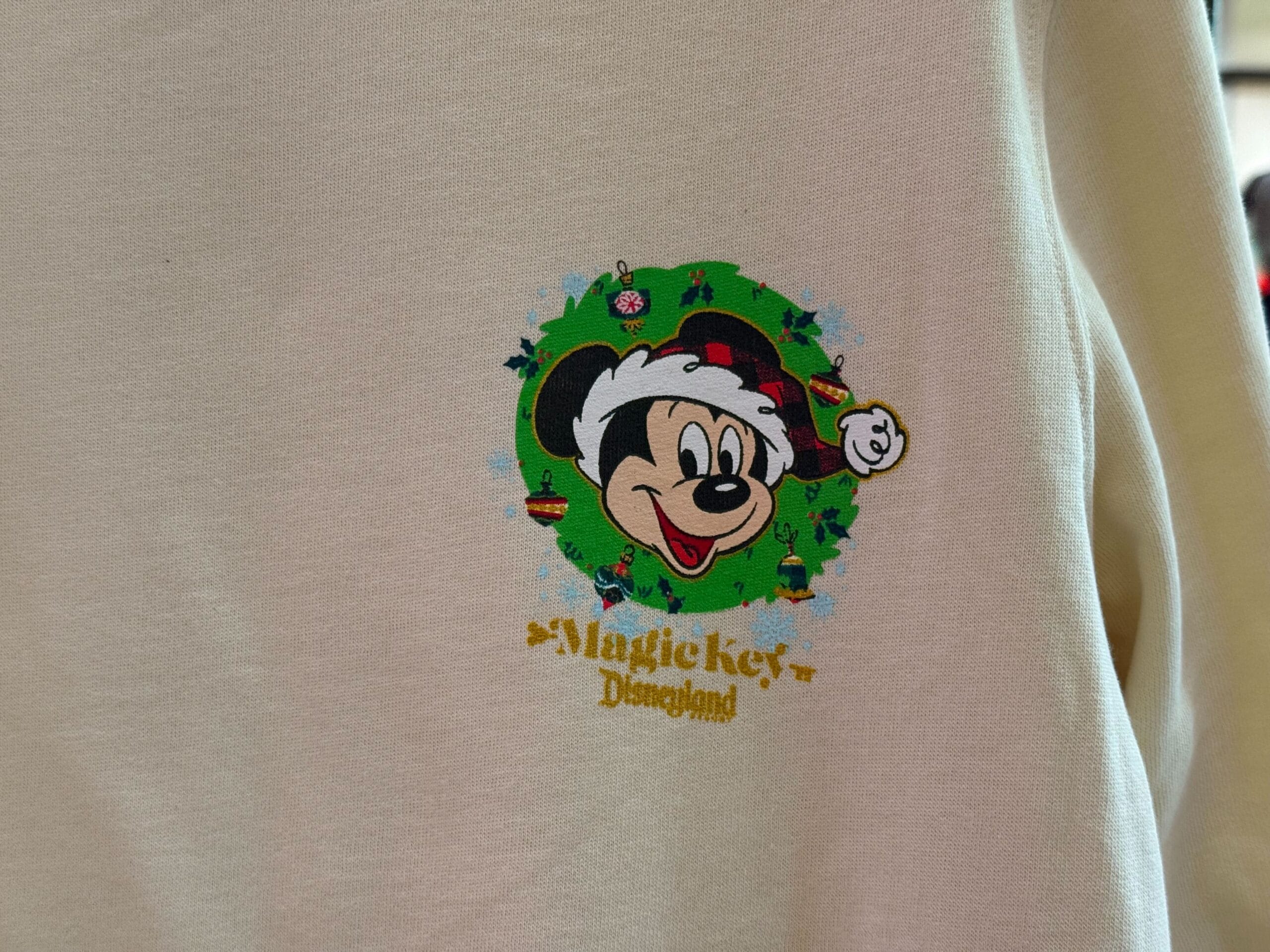 Mickey Mouse in a Santa hat on a cream "Magic Key Disneyland" shirt—festive merch exclusive to Disneyland, not Walt Disney World.