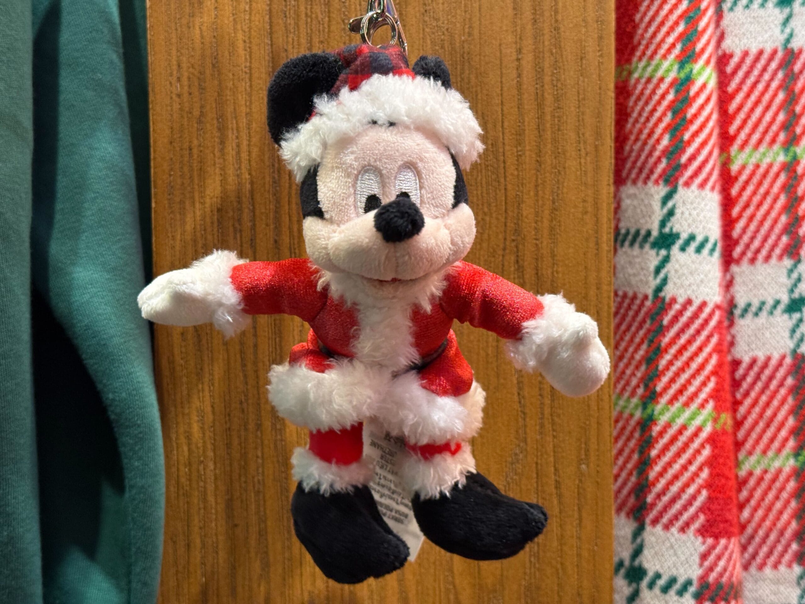 Plush Mickey Mouse in a Santa suit hangs with Disneyland holiday gifts—Disneyland’s castle differs from Magic Kingdom’s grander style.
