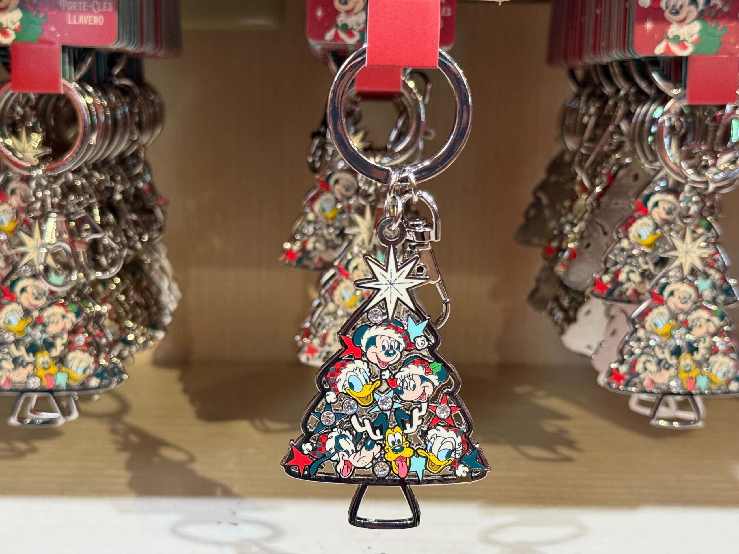 Christmas tree keychain from the Peppermint Collection displays Disney characters, reminiscent of festive park holiday decor.