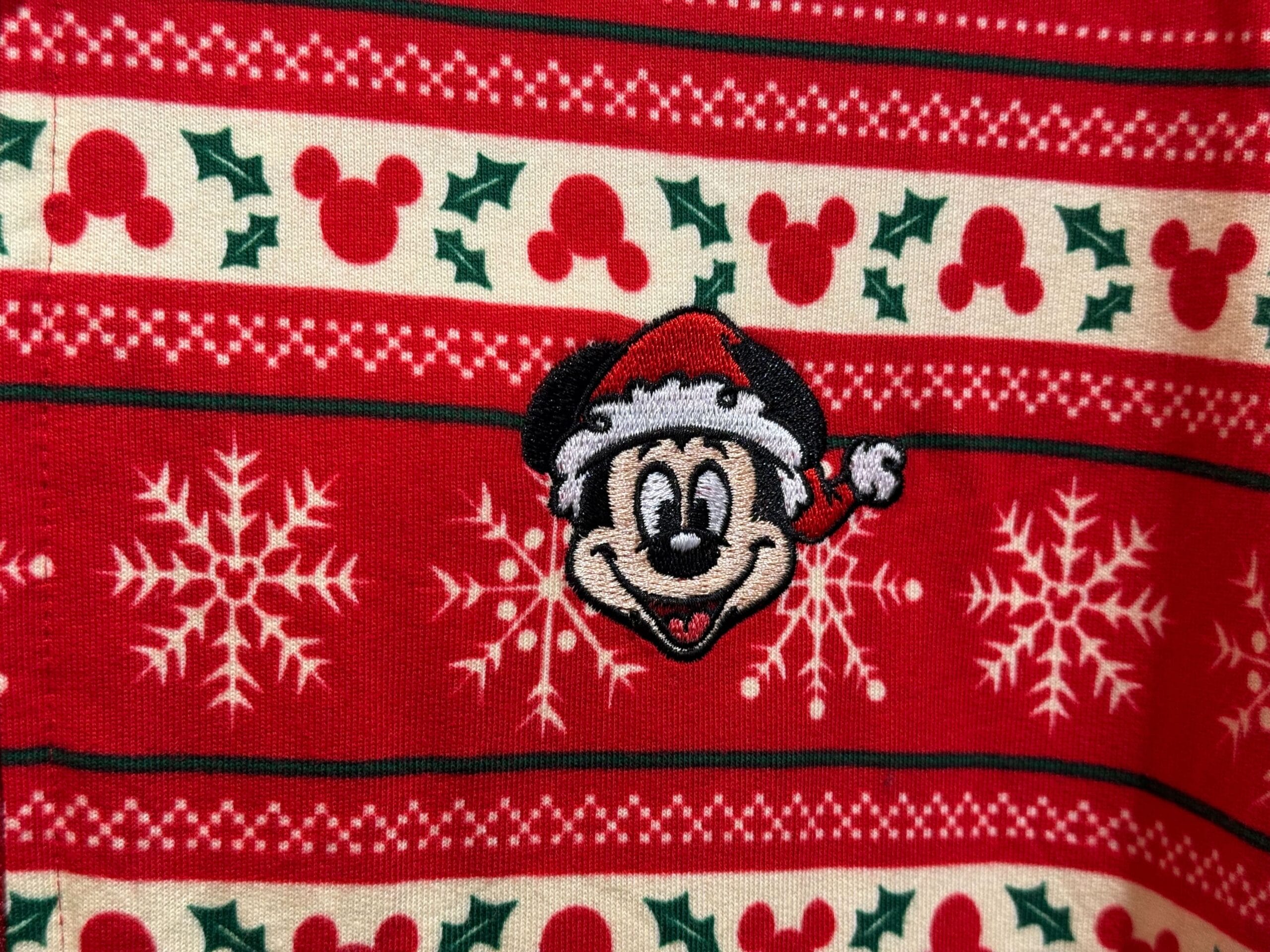 Red Christmas sweater from the Peppermint Collection with snowflakes, holly, and Mickey Mouse in a Santa hat, similar to designs seen at Disneyland parks.