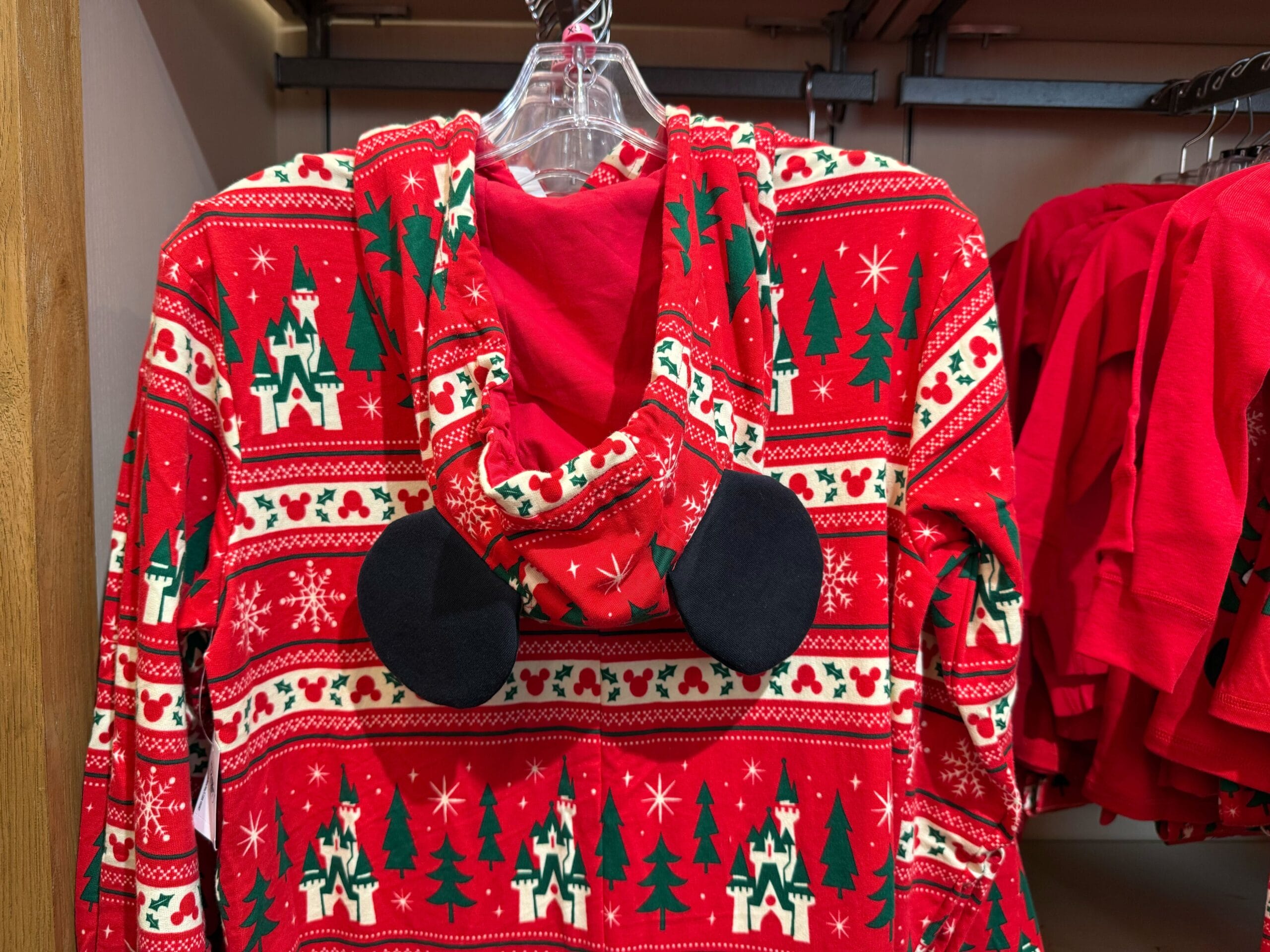 Red holiday hoodie from the Peppermint Collection with Christmas trees, snowflakes, mouse ears, and Disneyland-style castles design.