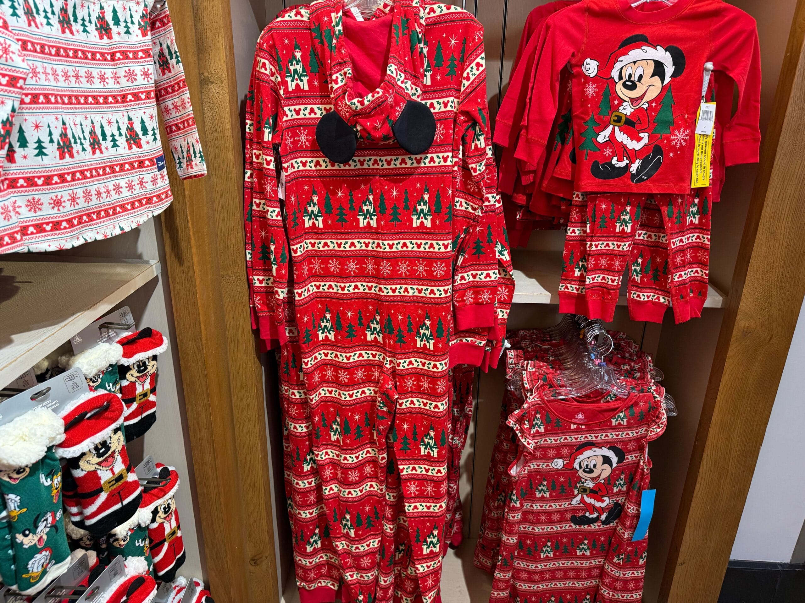 Red Christmas pajamas with Mickey Mouse from Disneyland’s Peppermint Collection, displayed on a store rack near park merchandise.