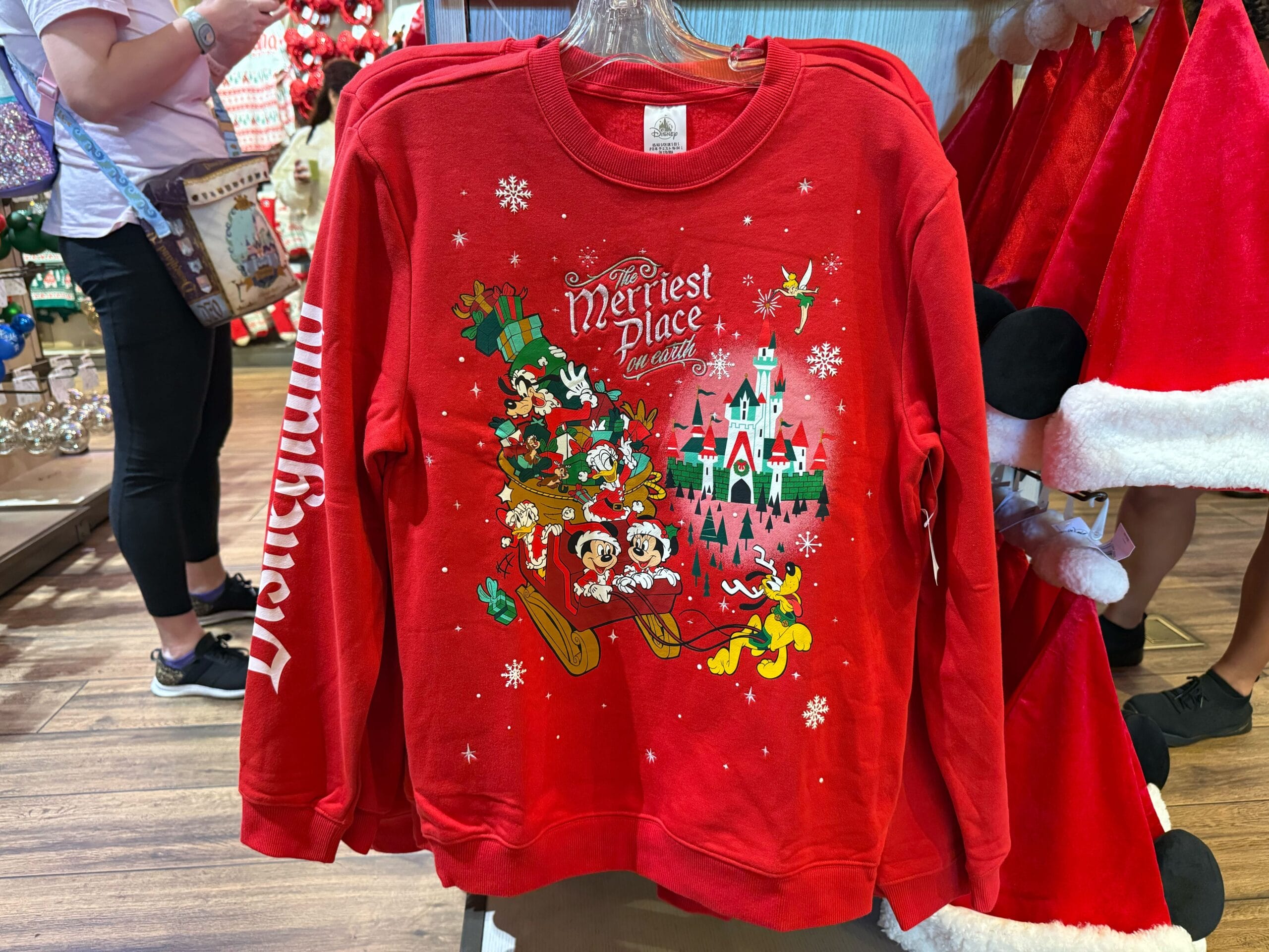 Red holiday Disneyland sweatshirt with Disney characters riding a sleigh, from the Peppermint Collection festive park merchandise.