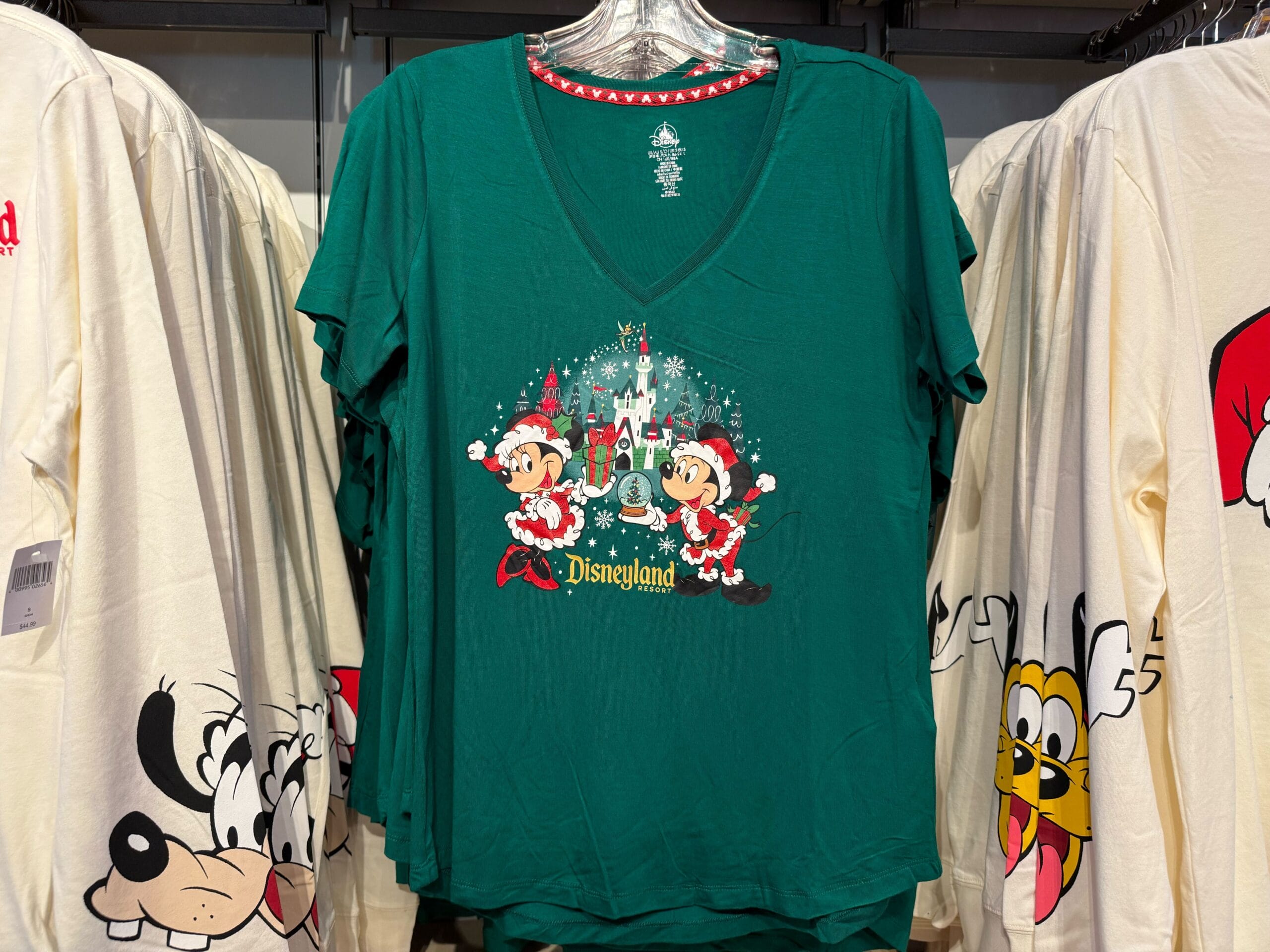 Green Disneyland Peppermint Collection shirt featuring Mickey, Minnie, and Pluto in festive outfits, displayed on a rack at the park.