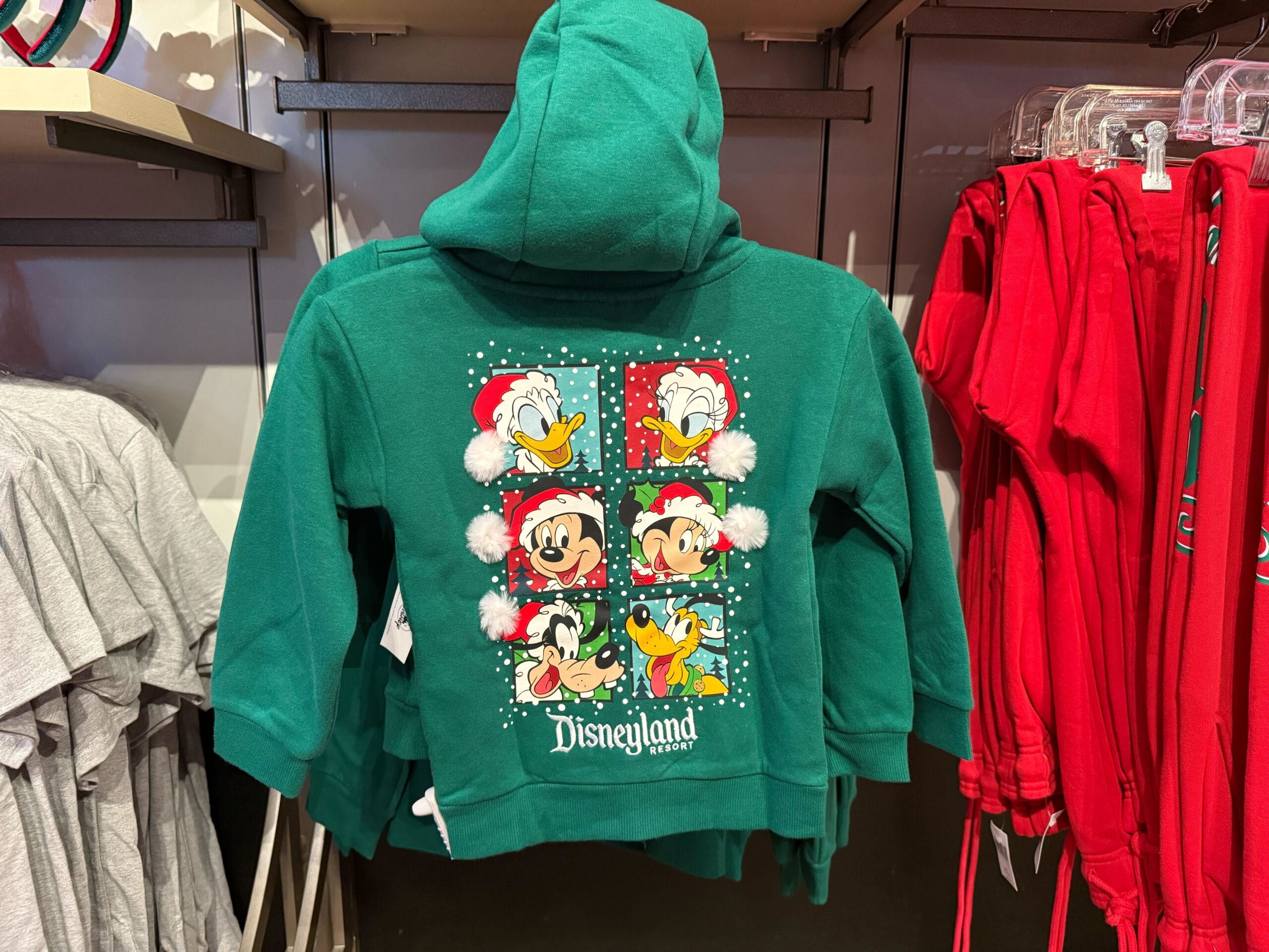 Green Disneyland hoodie with Mickey and friends in Santa hats, part of holiday merch—features Disneyland branding, not Cinderella Castle.