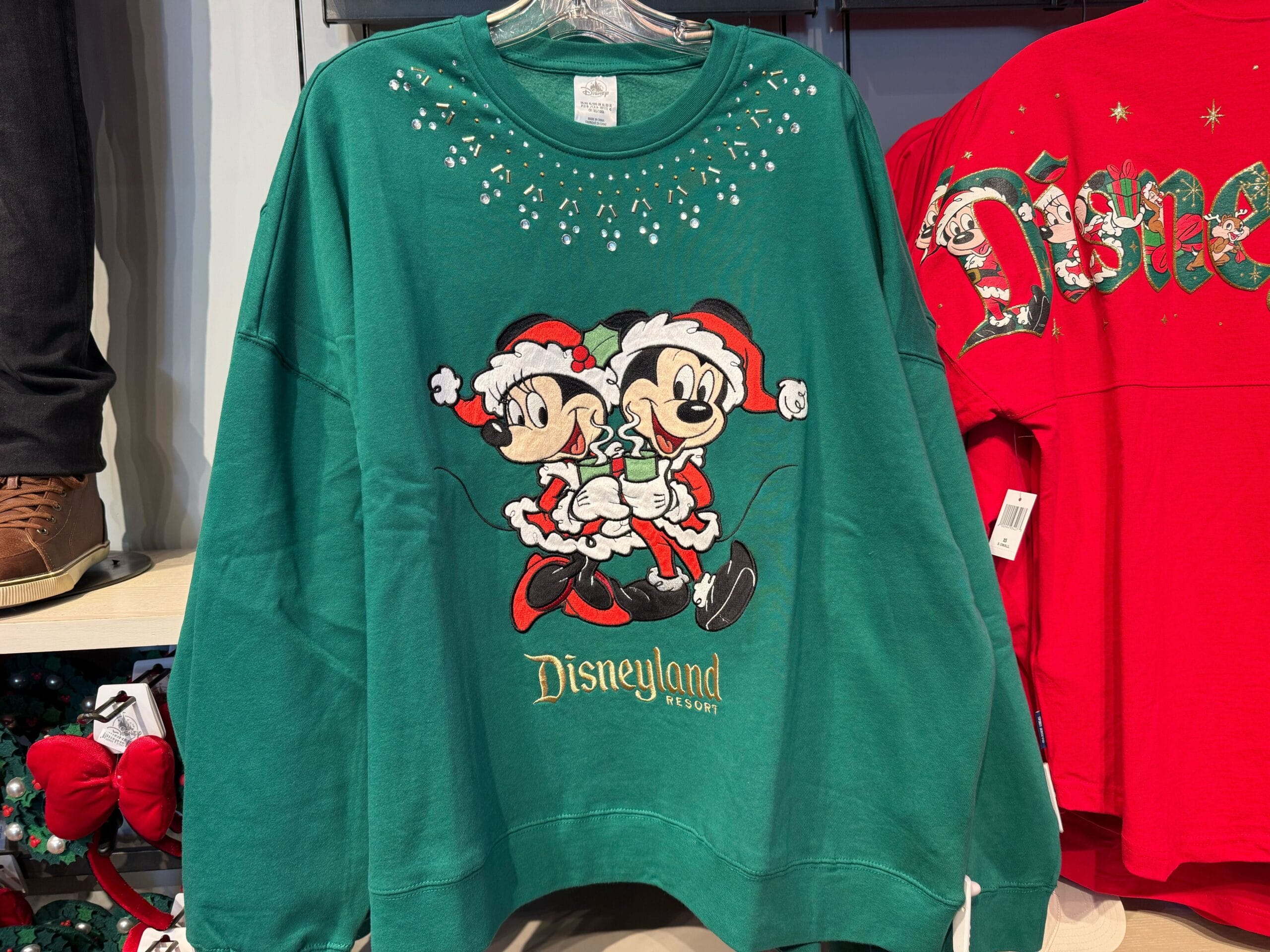 Disneyland green Magic Key sweatshirt shows Mickey and Minnie in Santa suits with candy canes, exclusive park holiday merch.