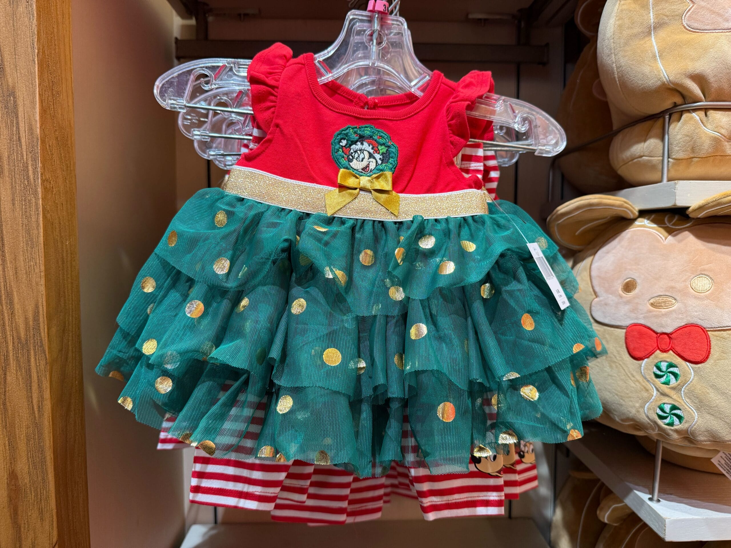 Red and green festive dress with gold polka dots, ruffled skirt, plus a Mickey-shaped Disneyland Christmas wreath from park merchandise.
