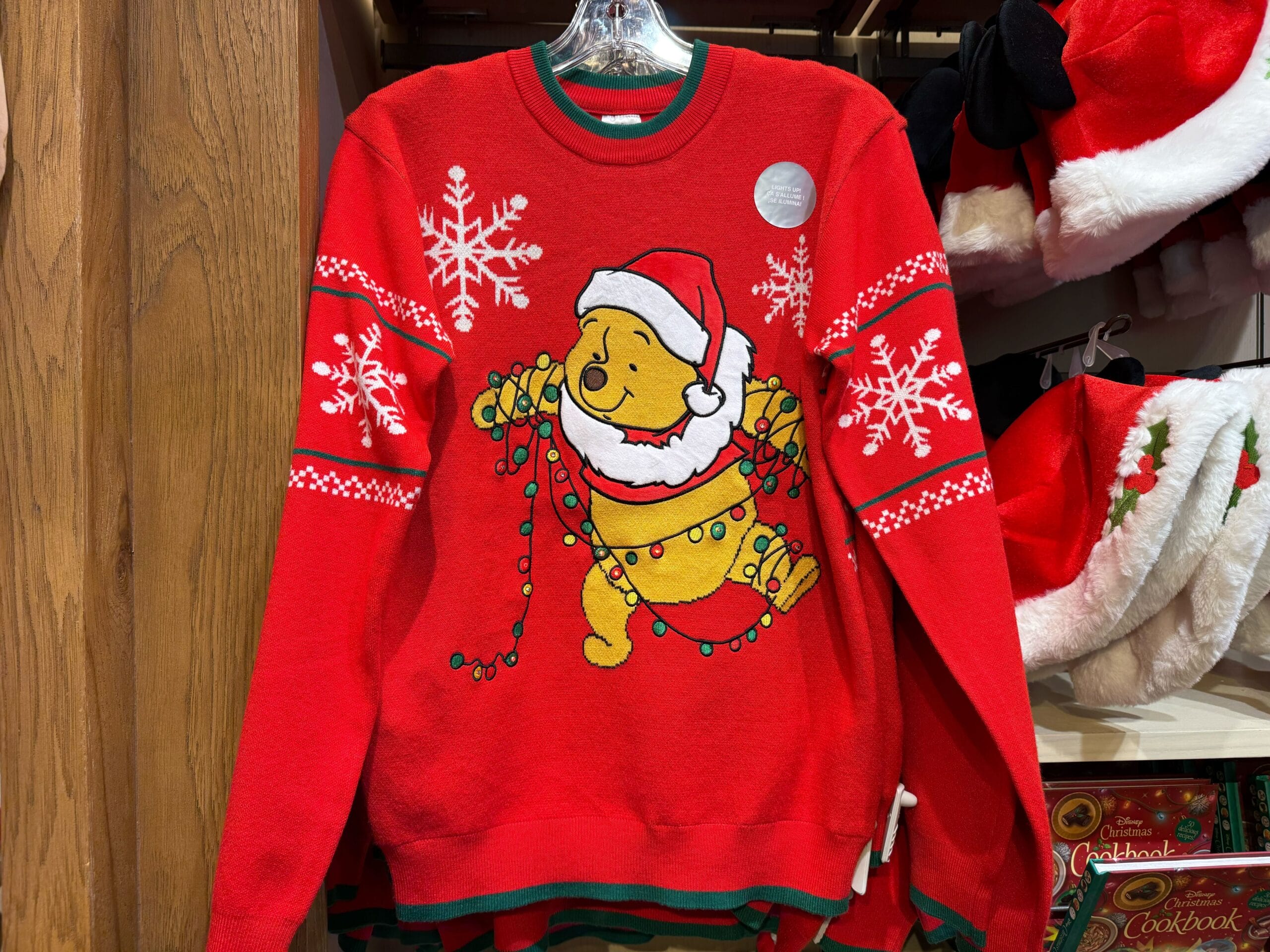 Red Christmas sweater from the Peppermint Collection featuring Winnie the Pooh tangled in lights, festive Disneyland park merch.