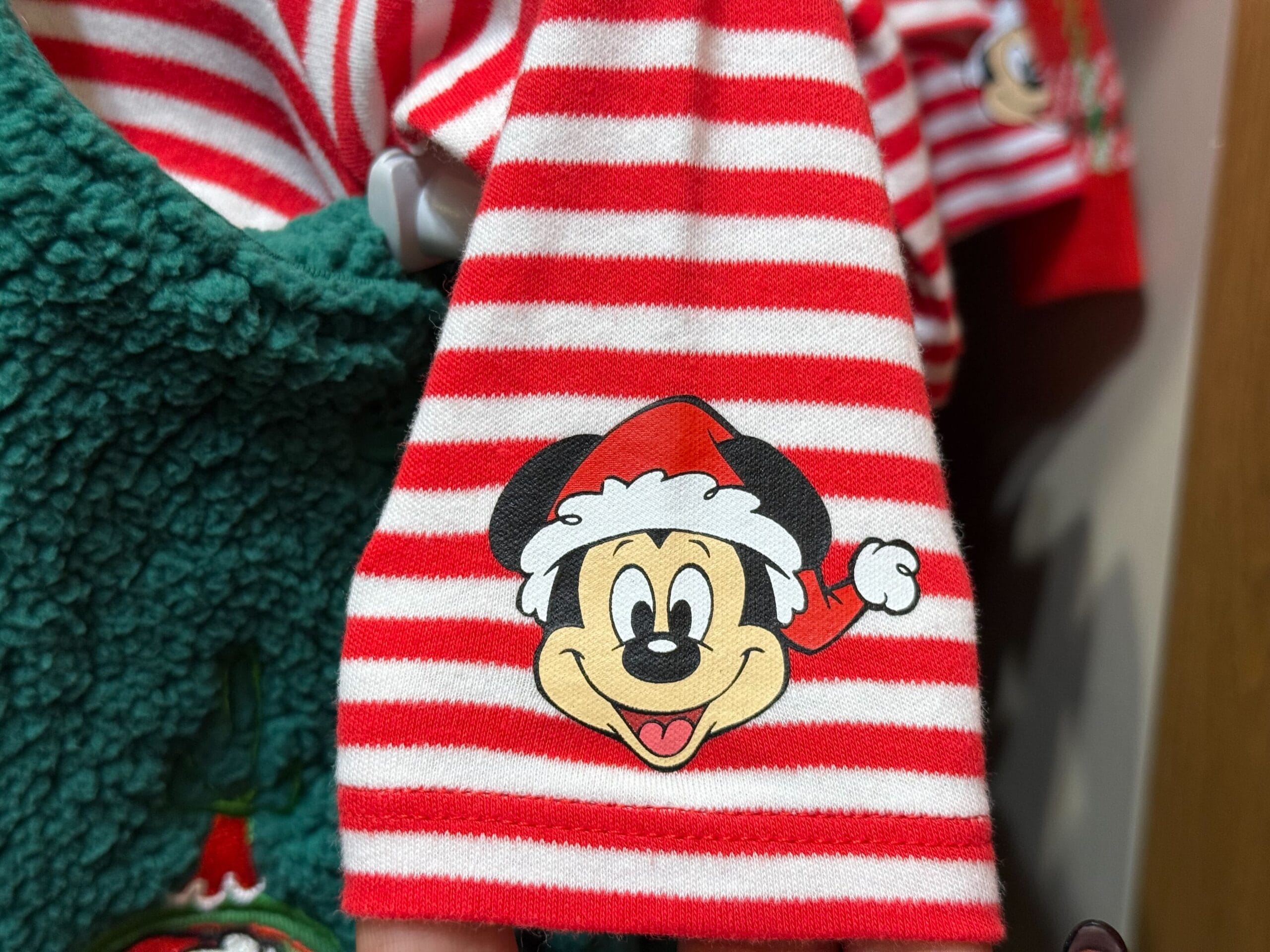 Red and white striped Peppermint Collection fabric with Mickey Mouse in a Santa hat, set against green; classic Disney holiday style.