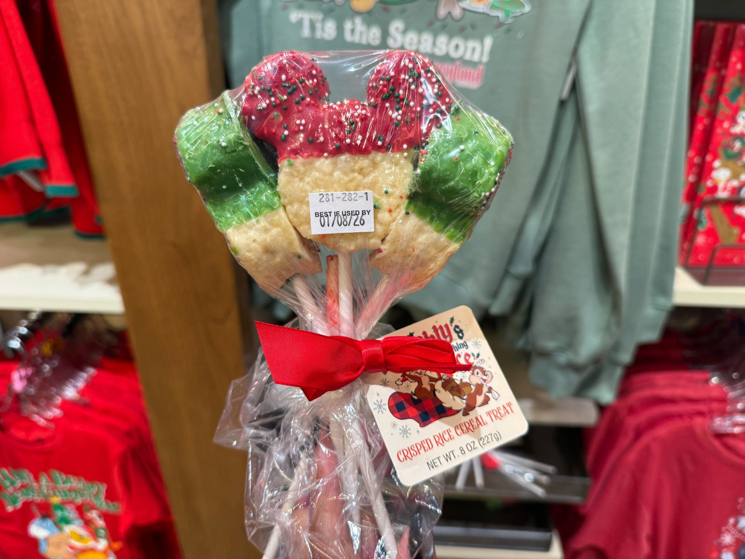 Three Mickey-shaped crispy rice treats from Disneyland’s Christmas lineup, each wrapped in clear plastic with a festive red ribbon.