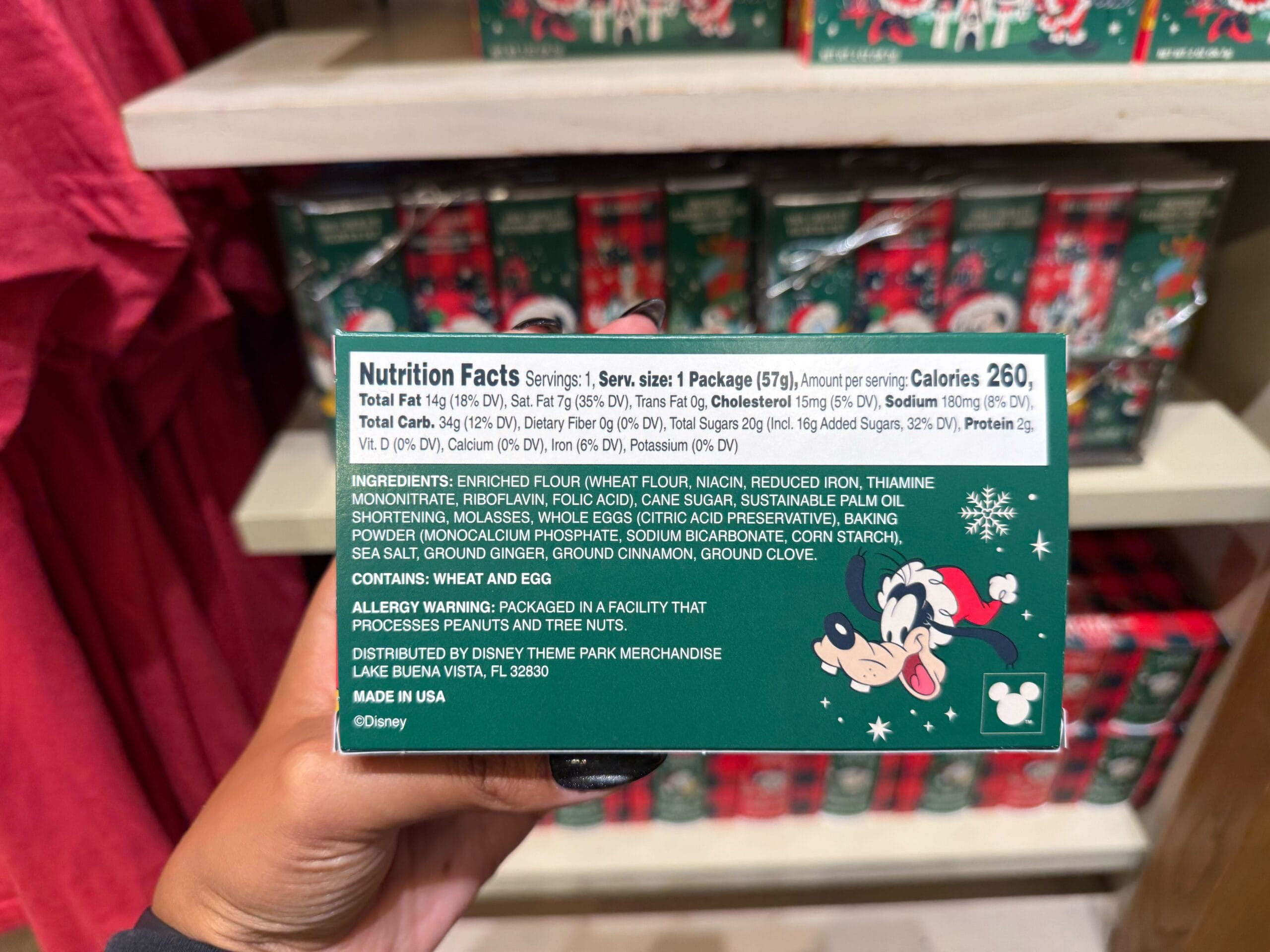 A hand holds a Disney holiday Peppermint Collection box with nutrition facts, Mickey Mouse in the corner, like park treats.
