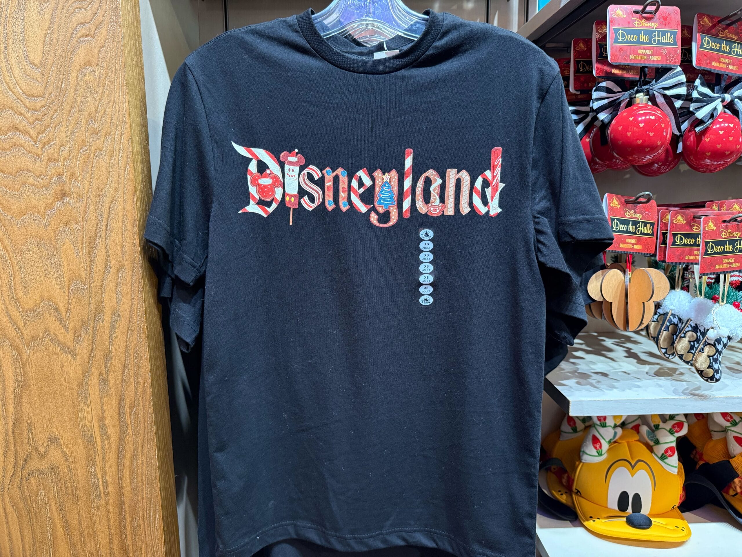 Black Disneyland Resort tee with Disney icon letters, beside holiday merch—no castle details to compare among Disney parks shown.