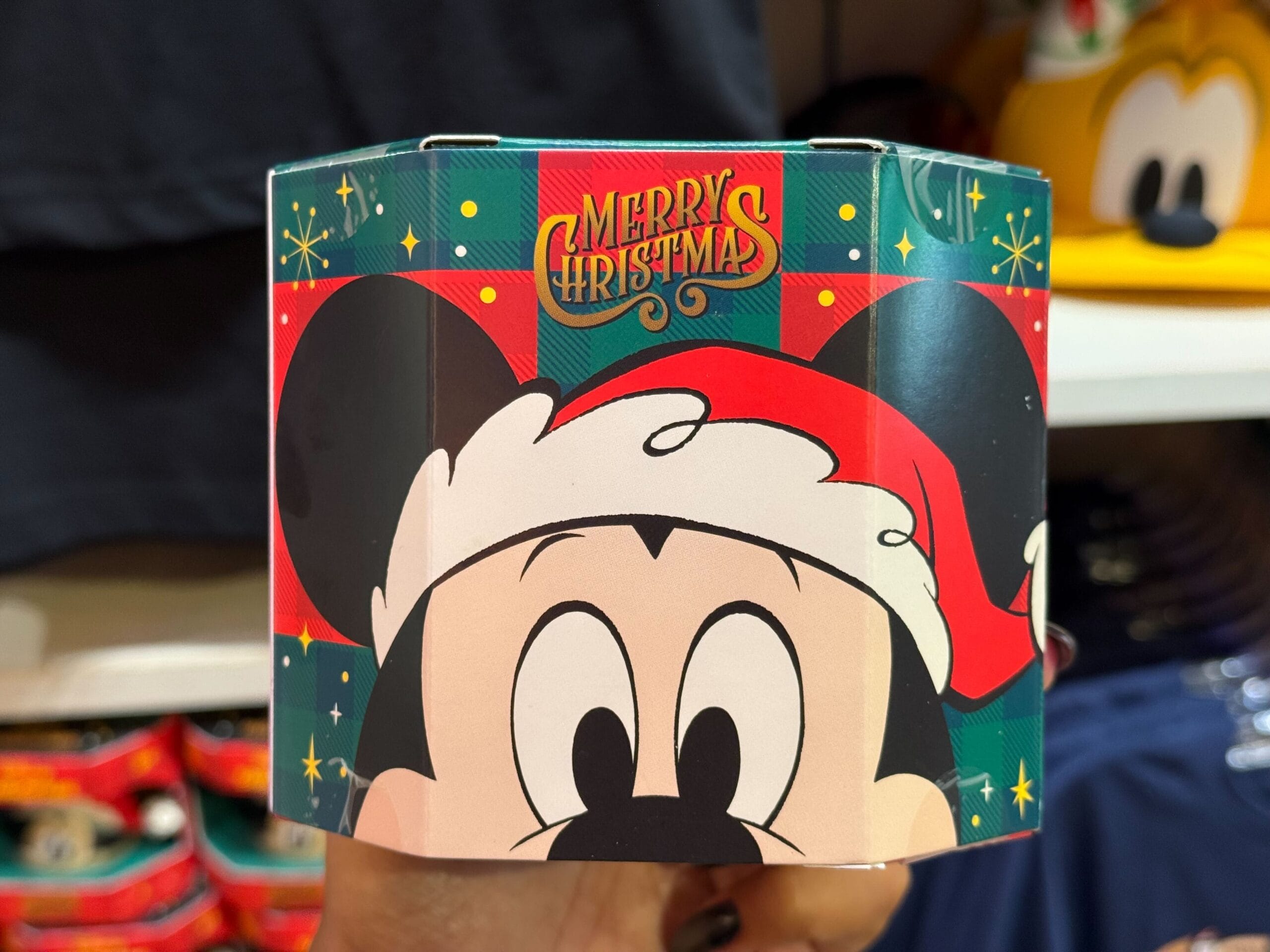 A “Merry Christmas” sign with Mickey Mouse in a Santa hat, from the Peppermint Collection at a Disney park’s festive display.