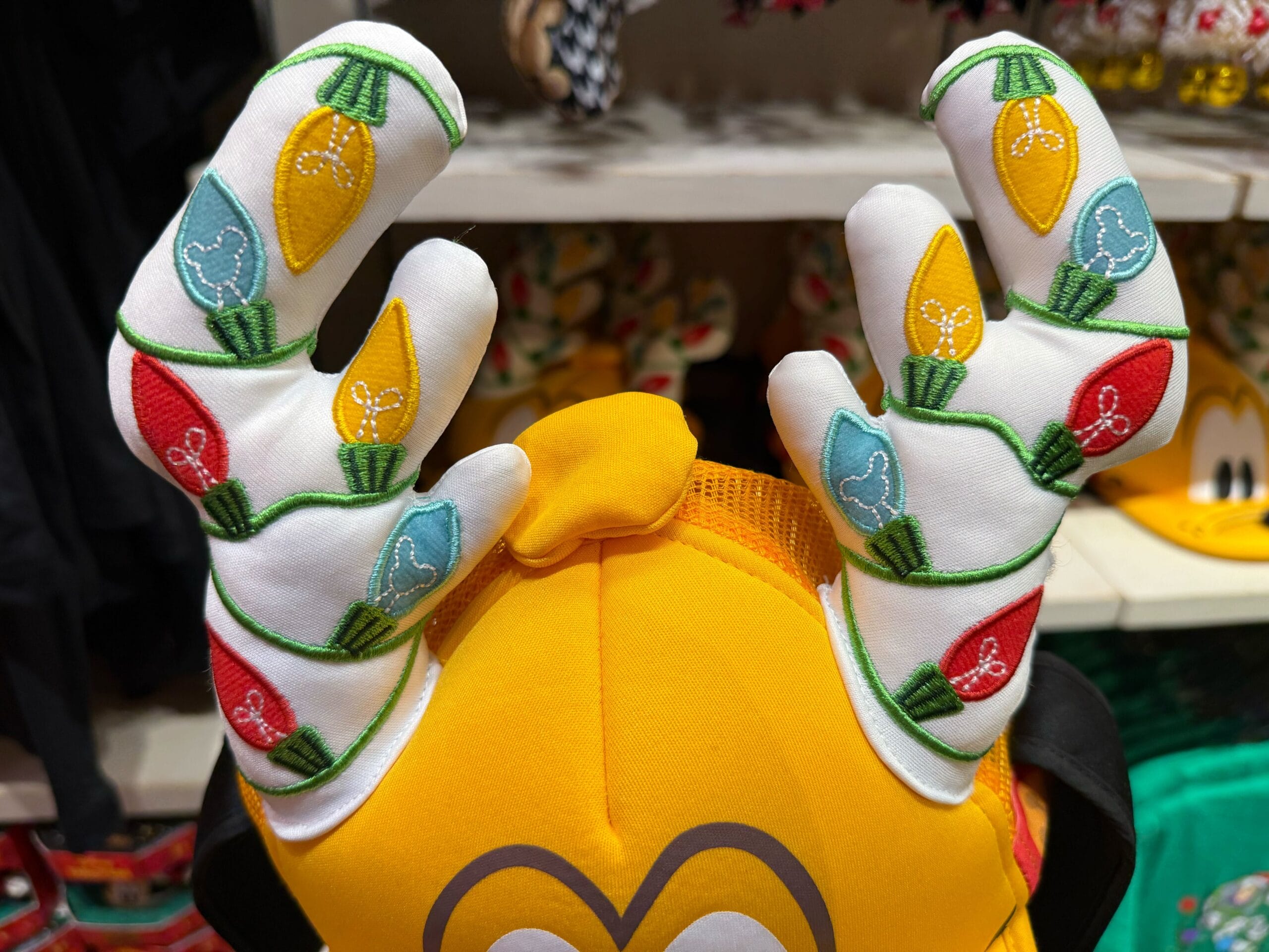A yellow hat with antlers, colorful holiday lights, white Mickey icons, and festive flair sold at Walt Disney Parks.