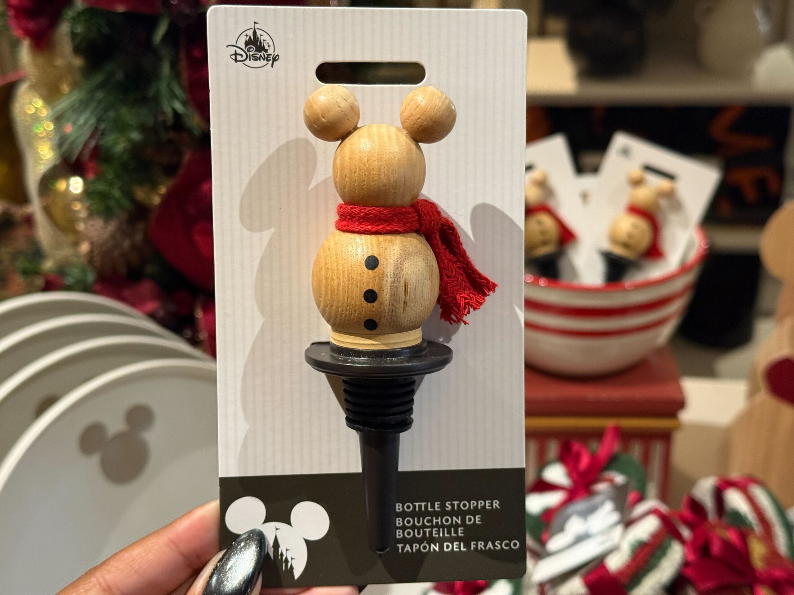 A wooden Mickey Mouse bottle stopper sporting a red scarf, featured in Disneyland Resort’s Christmas collection, no castle in view.
