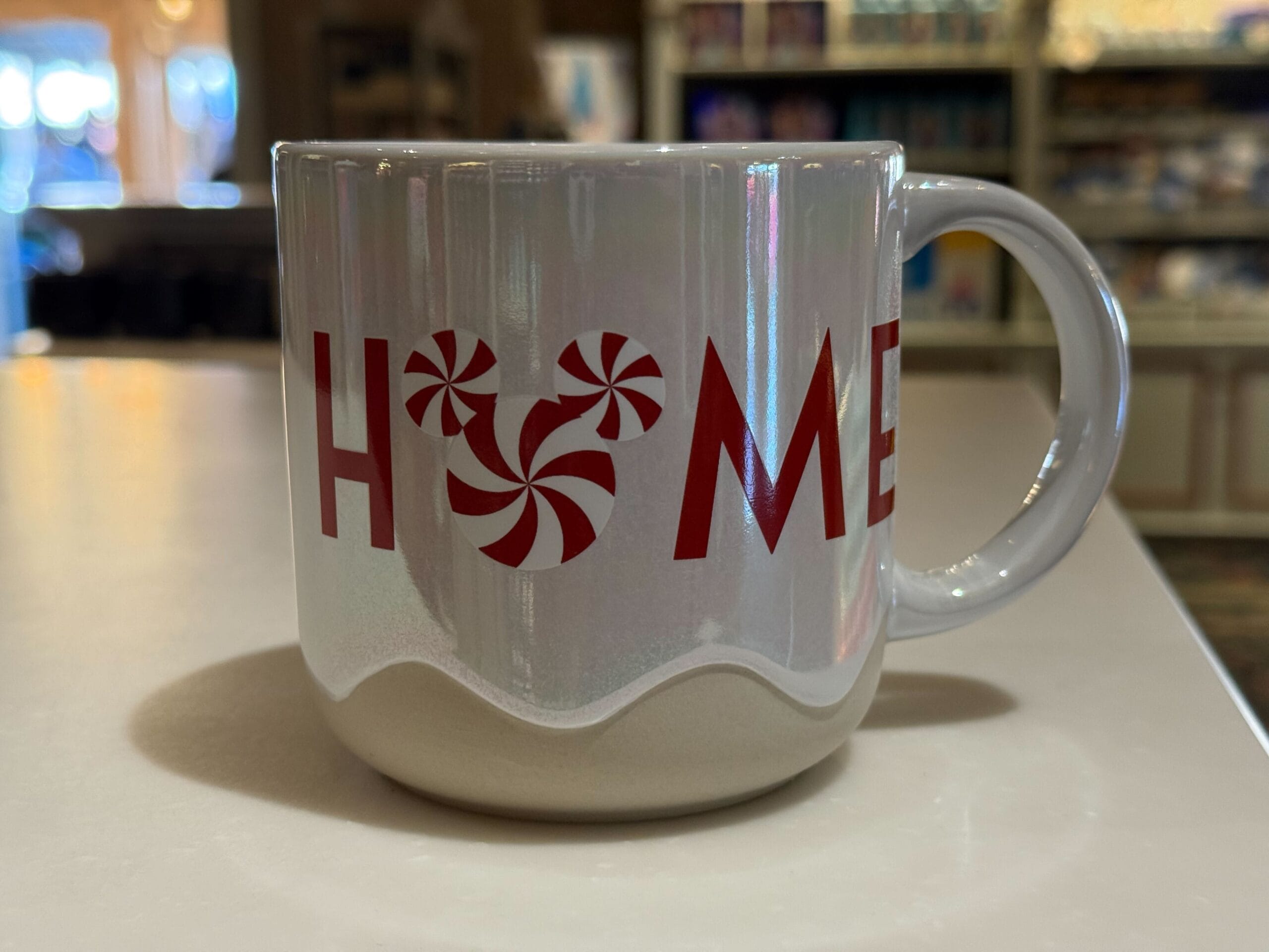 White mug reads "HOME" with a Mickey peppermint "O"—a cheery Disneyland Resort holiday item perfect for festive park mornings.