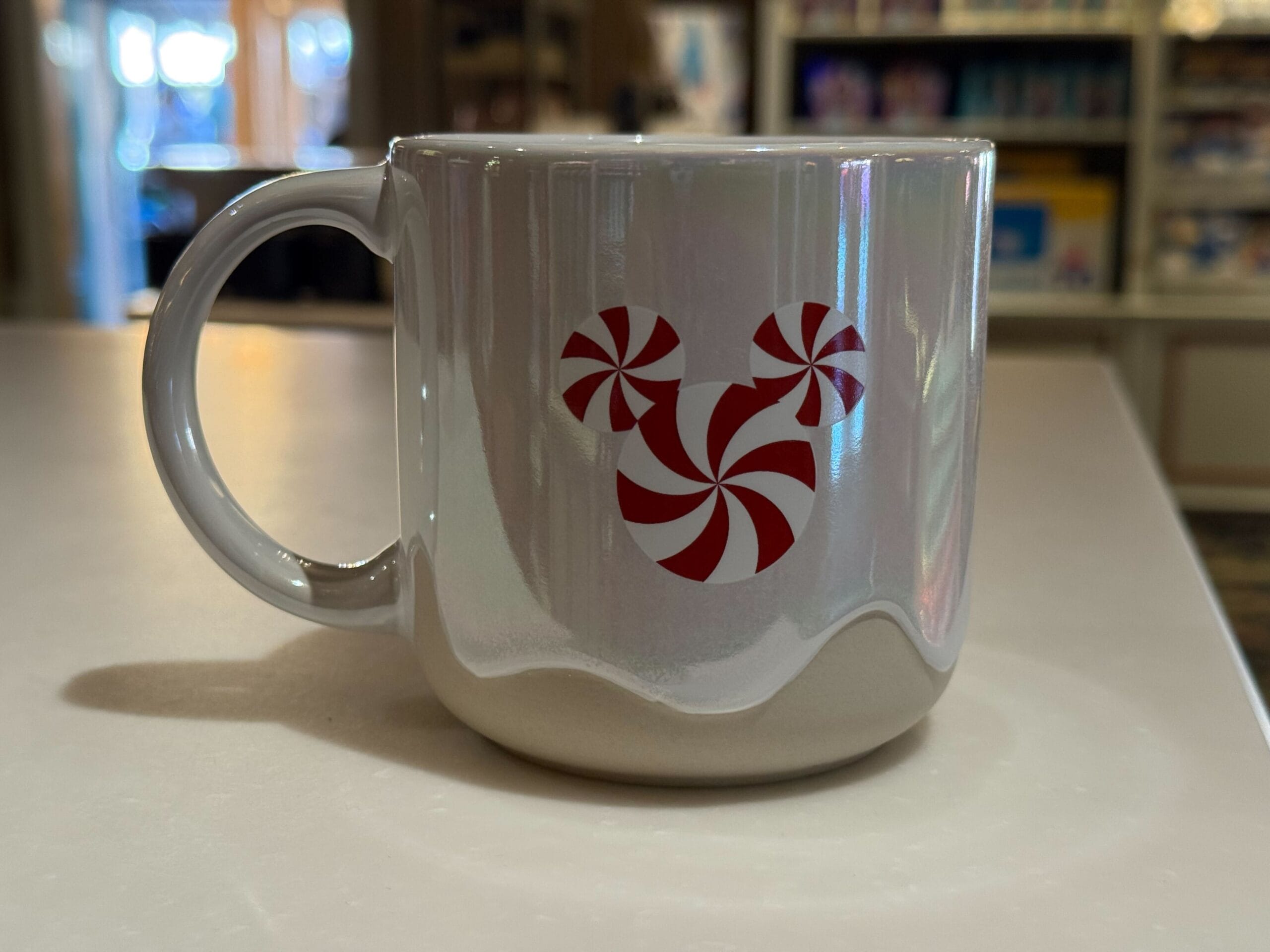 A white mug with a red peppermint Mickey Mouse, festive Christmas merch at Disneyland—distinct from the classic Disney World designs.
