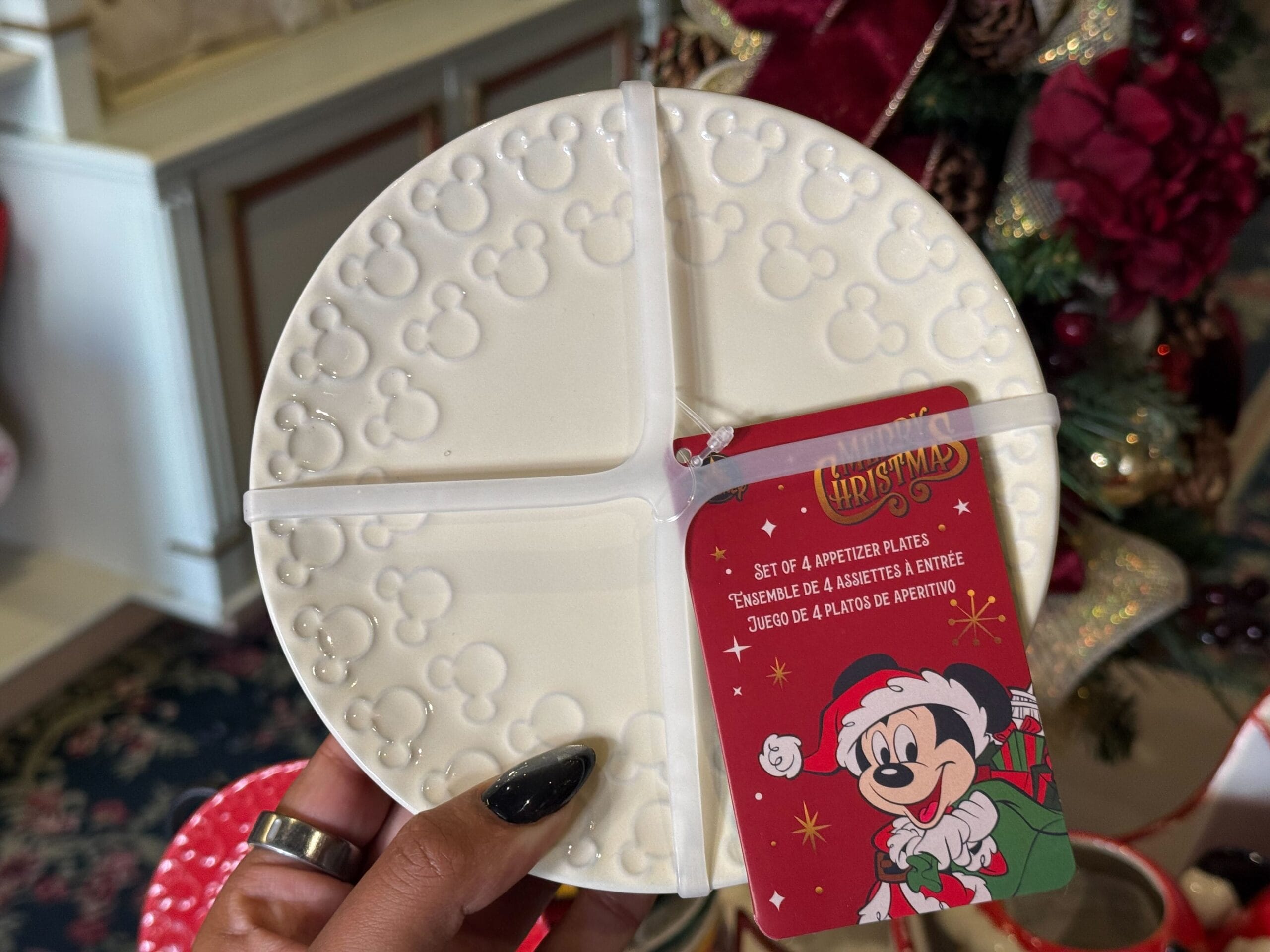 Hand holding a white appetizer plate with embossed Mickey heads, new Christmas merchandise at Disneyland—no castle like WDW's.