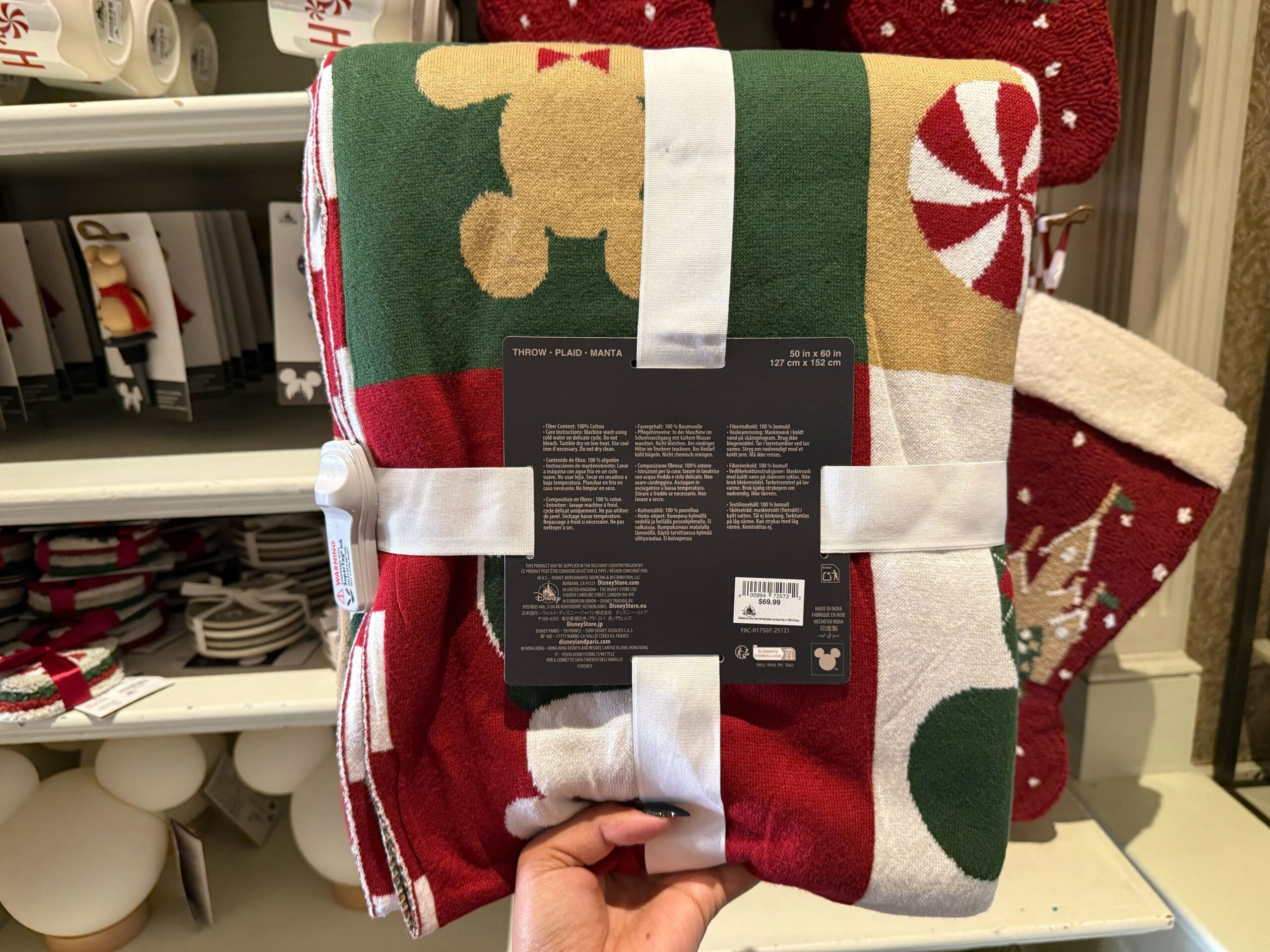 A hand displays a holiday Mickey Mouse blanket, among Disneyland Resort’s Christmas merchandise—exclusive to this park’s collection.