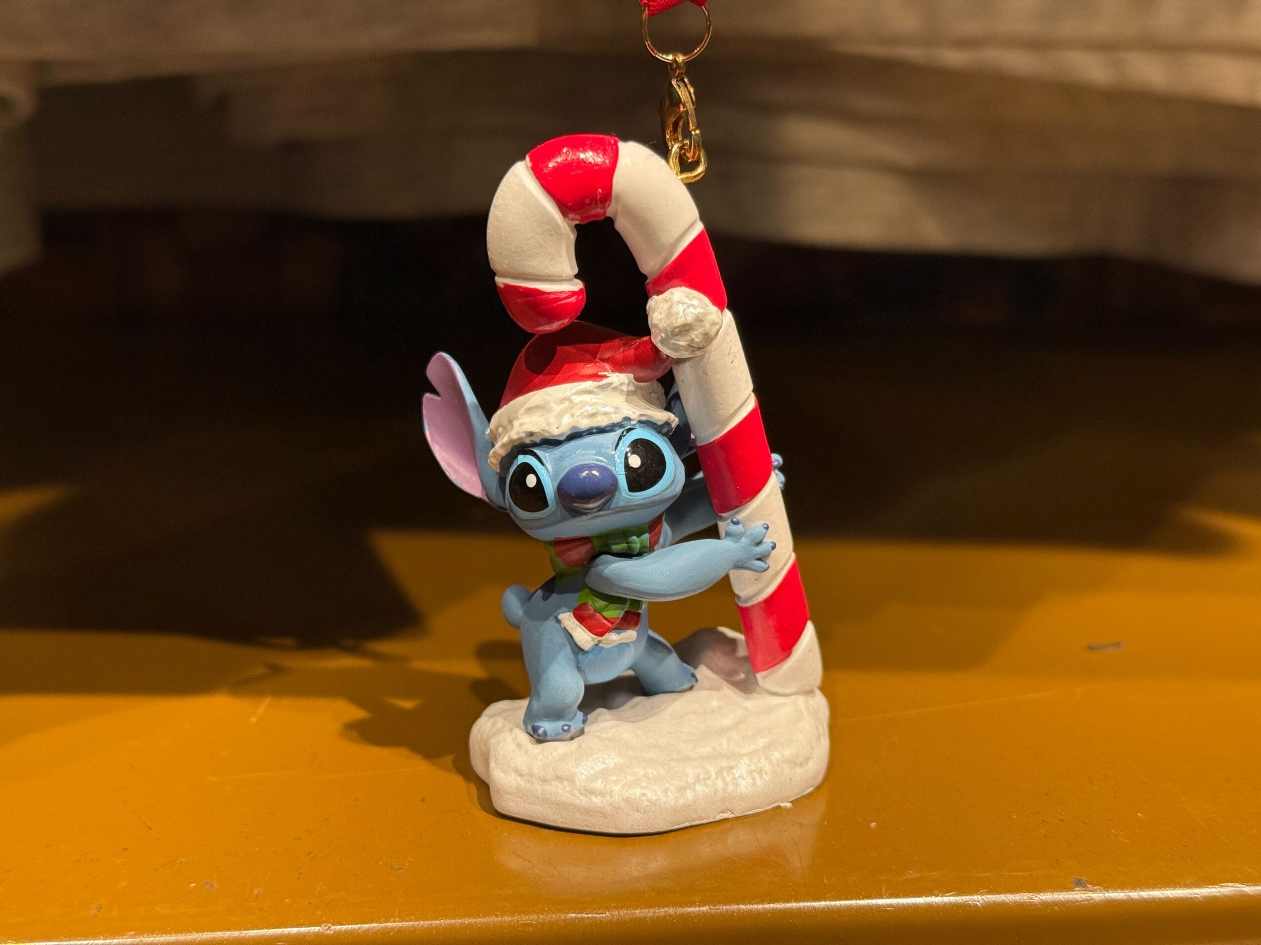 A blue cartoon character in a Santa hat hugs a candy cane—great Disneyland merch, especially for fans of the Anaheim park’s castle.