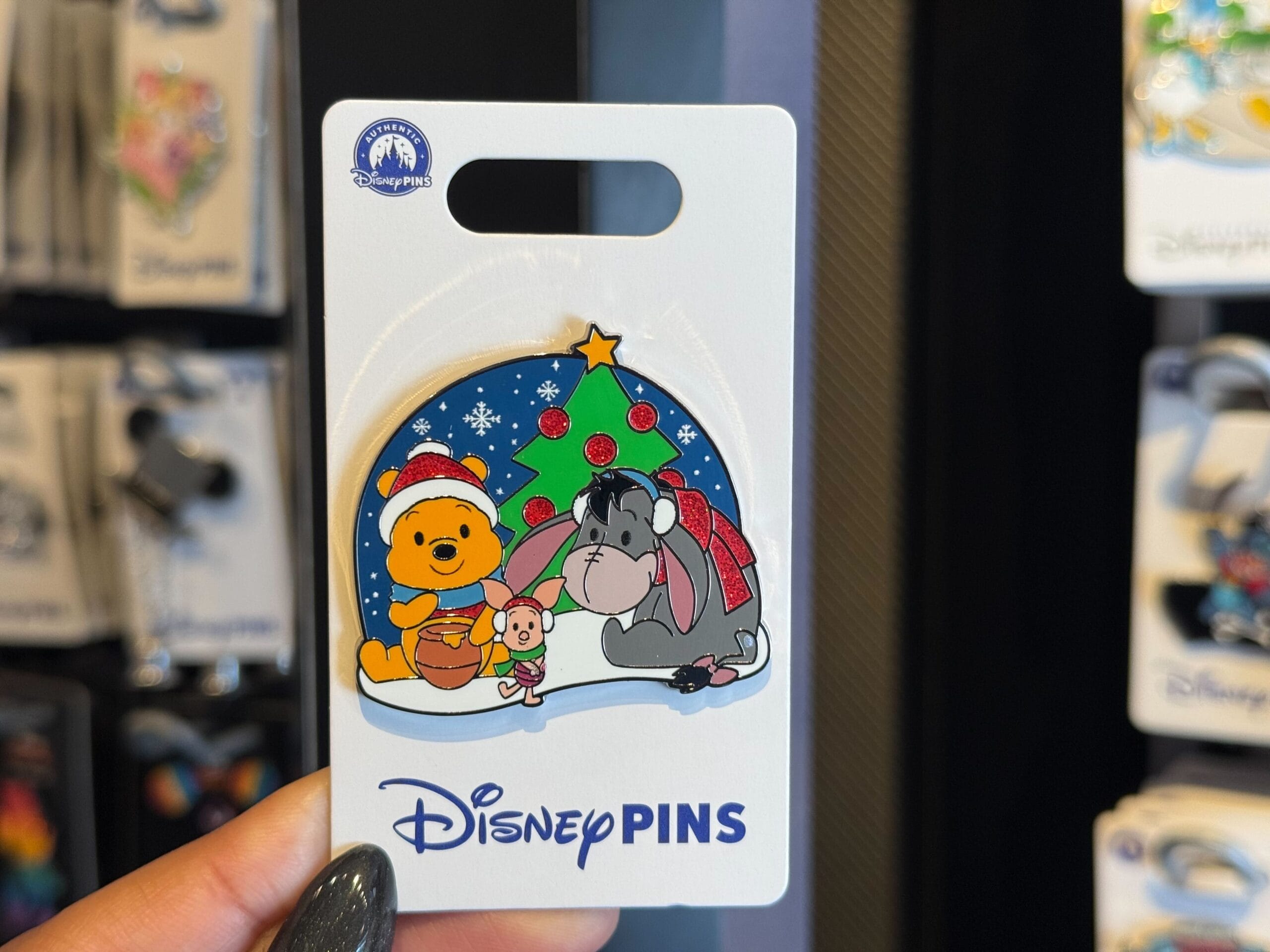 A Disneyland Resort pin with Winnie the Pooh, Piglet, and Eeyore gathered by a festive Christmas tree, no castle in view.