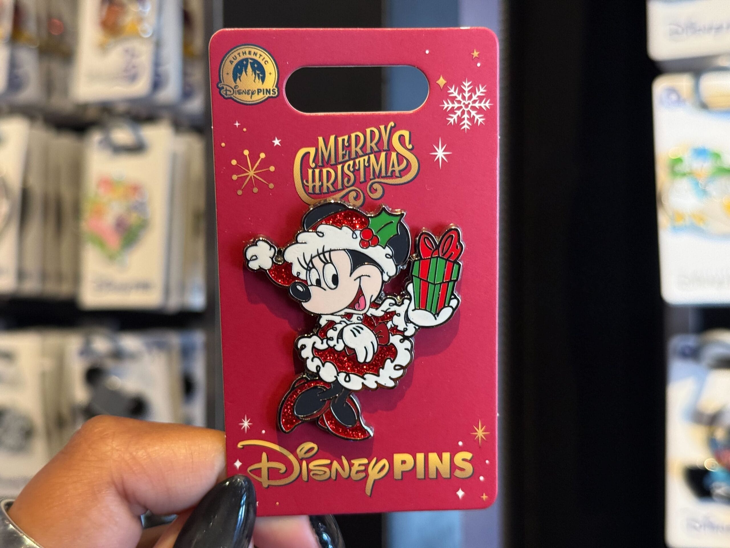 Disneyland Christmas: Minnie Mouse pin on festive red card, "Merry Christmas," "Disney Pins." No castle pictured for comparison.