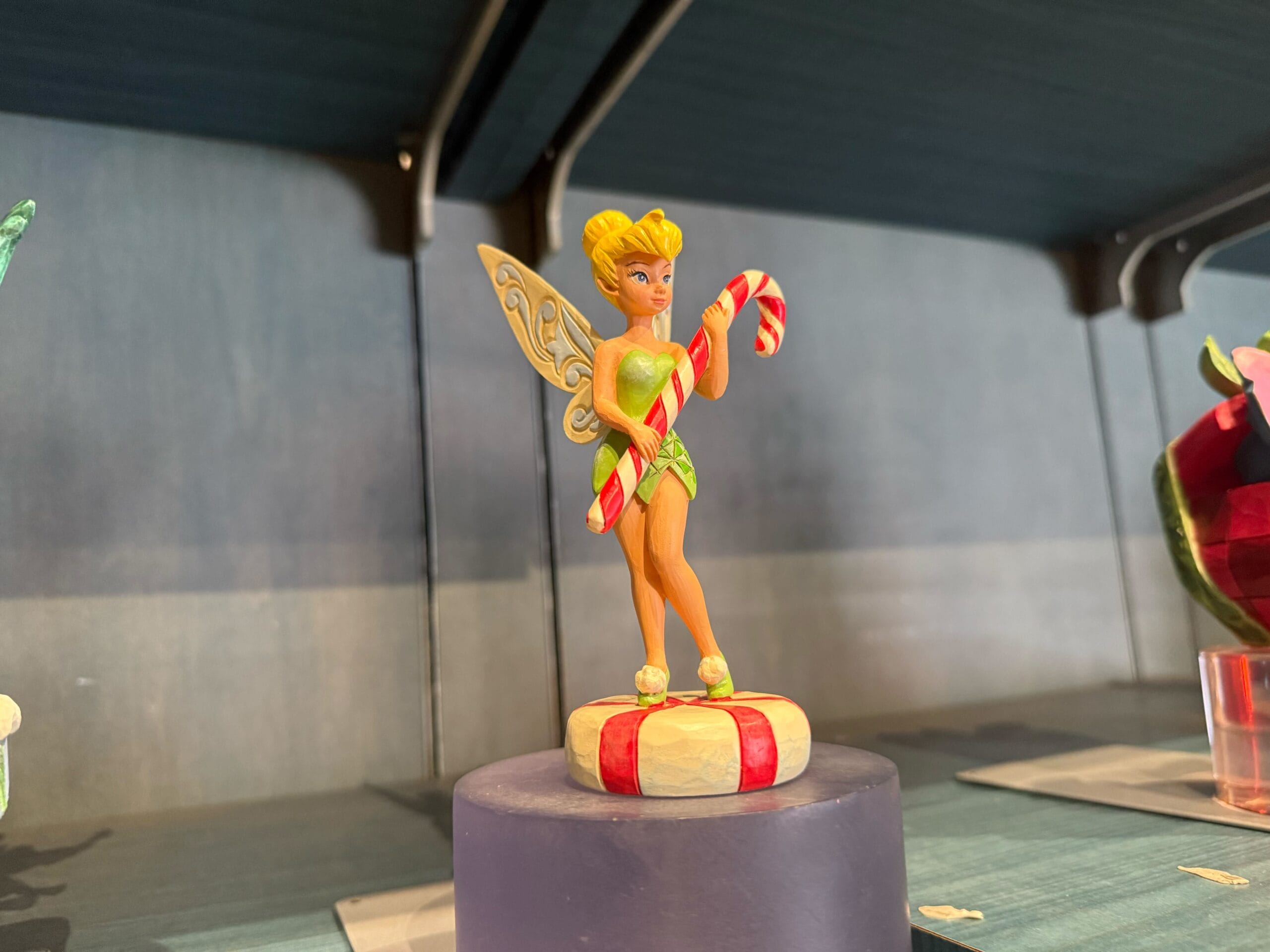 Tinkerbell figurine holding candy canes stands on a red and white present base, a festive new arrival at Disneyland Resort.