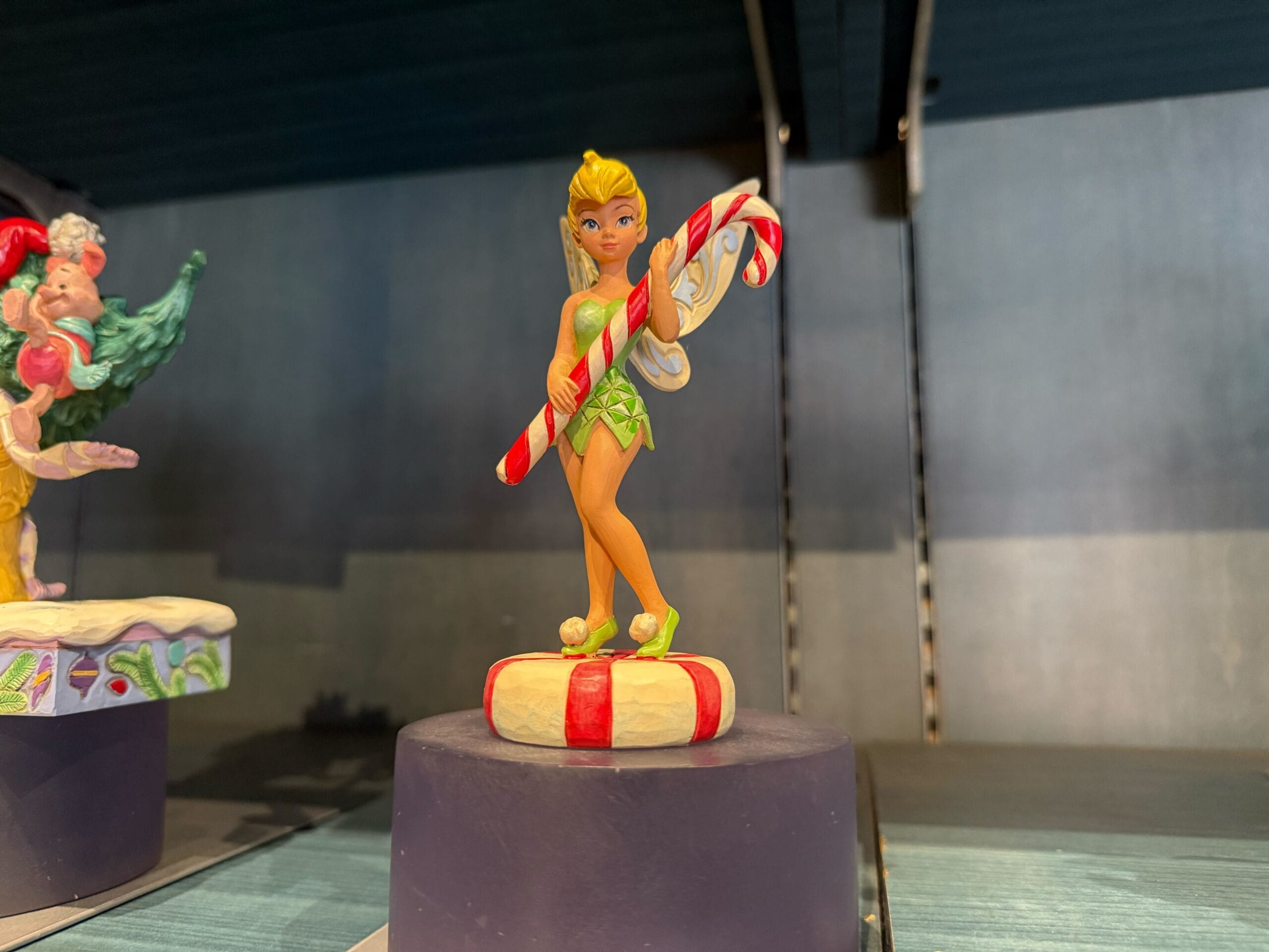 A Tinker Bell figurine with candy cane on a red and white striped base, from Disneyland Resort—home to the original Disney castle.