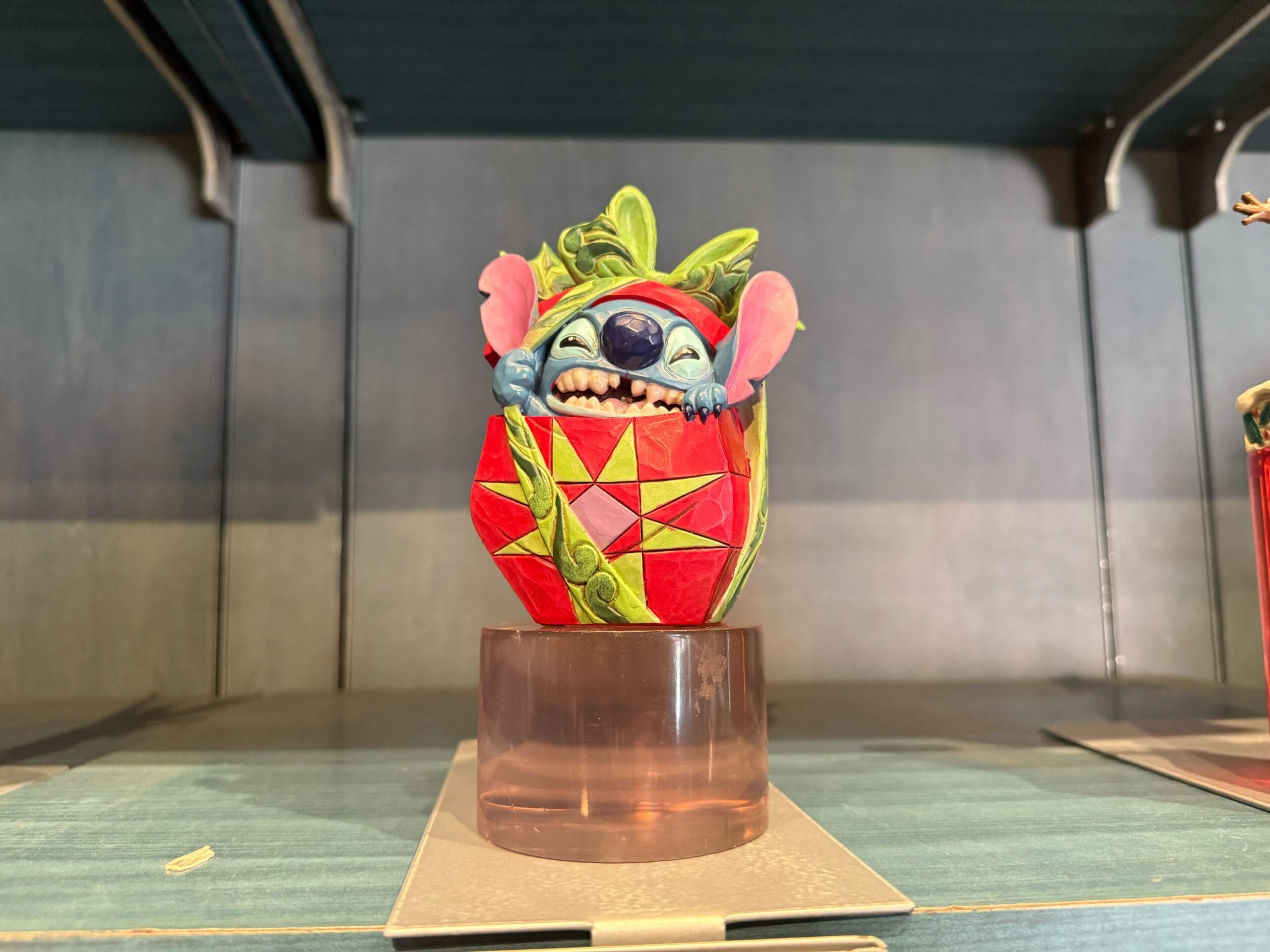 A vibrant figurine of Stitch peeking from a red egg brings cheerful Disney magic to your Disneyland Resort collection display.