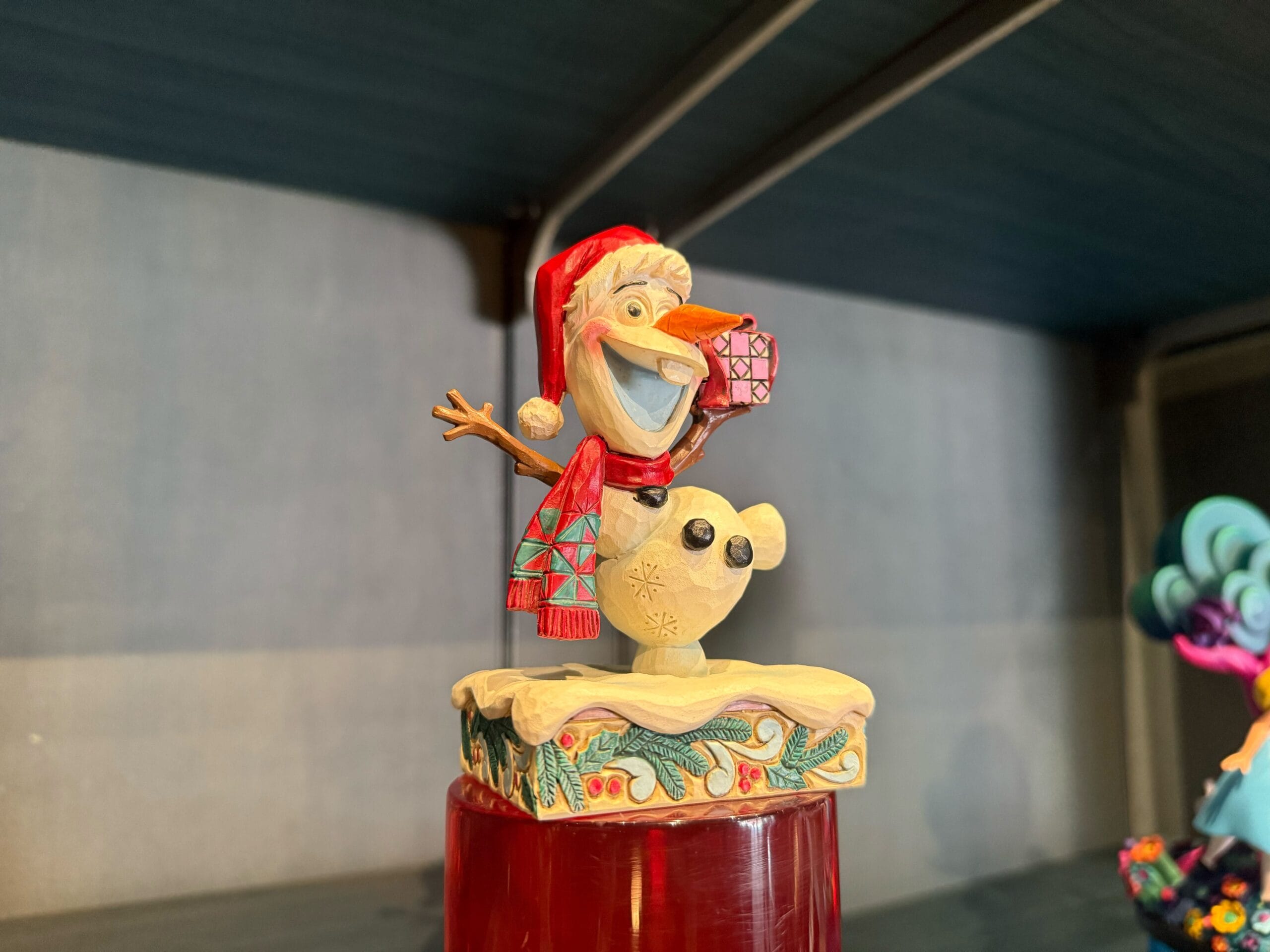 A cheerful Olaf figurine from Frozen among the new Christmas merch at Disneyland Resort—spot Santa hats but no Sleeping Beauty Castle nearby.