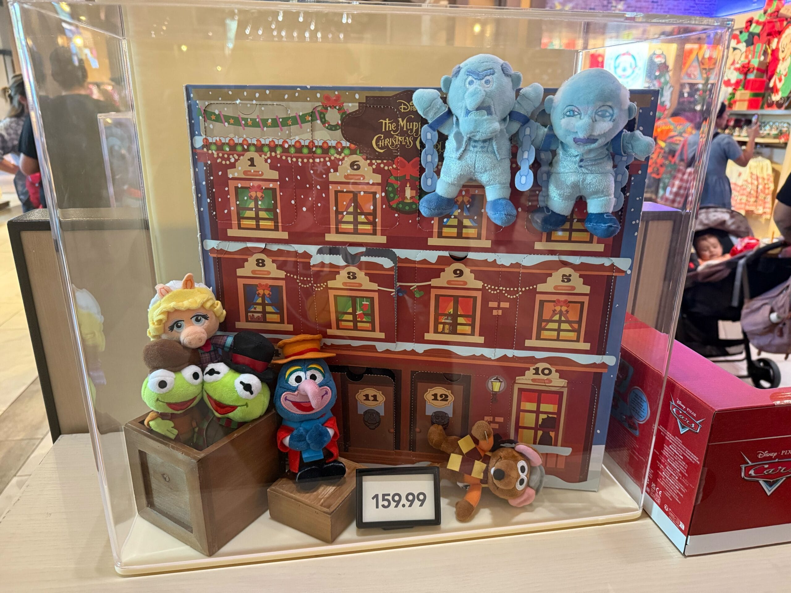 Disneyland Resort display case features new Muppet Christmas Carol plushies and $159.99 advent calendar—no castle in view.