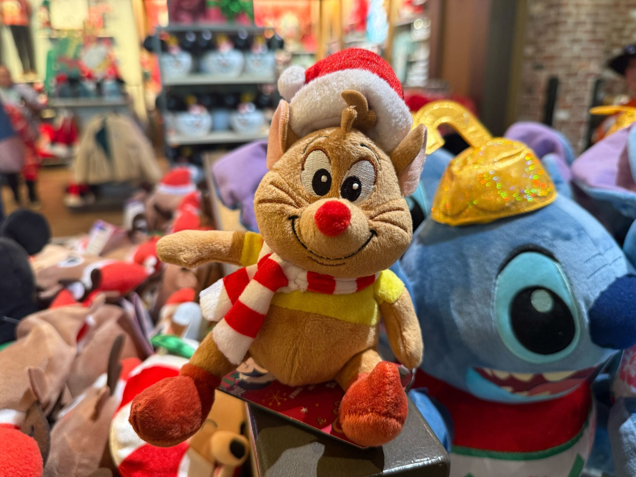 A plush reindeer toy in holiday attire is displayed with new Christmas merchandise at Disneyland Resort, near Sleeping Beauty Castle.