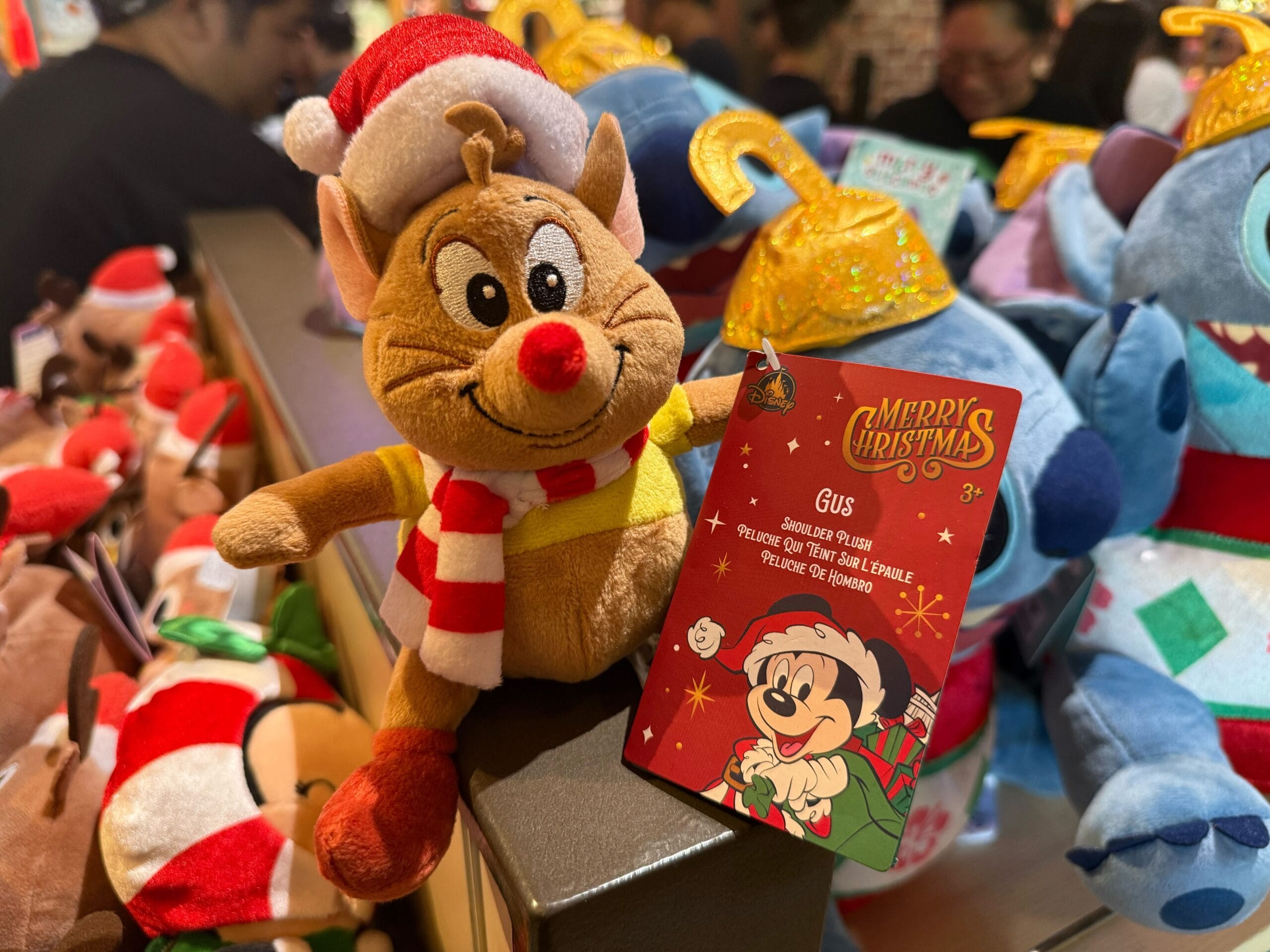 Gus from Cinderella in a Santa hat, festive Disneyland Resort merchandise surrounded by other plush toys—no castle in view.