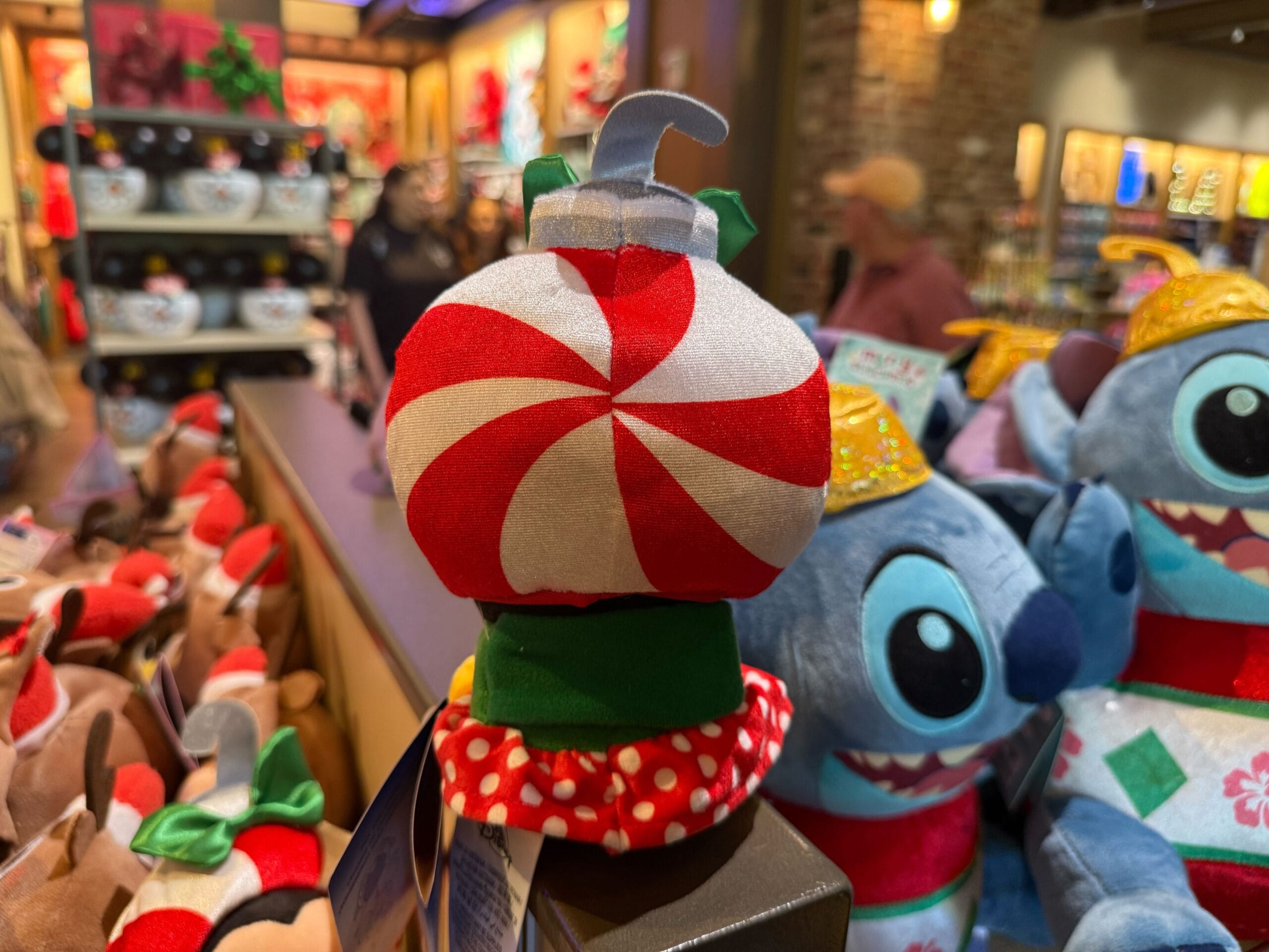 A plush peppermint ornament with a red and white swirl joins festive Christmas merchandise at Disneyland Resort, home to Sleeping Beauty Castle.