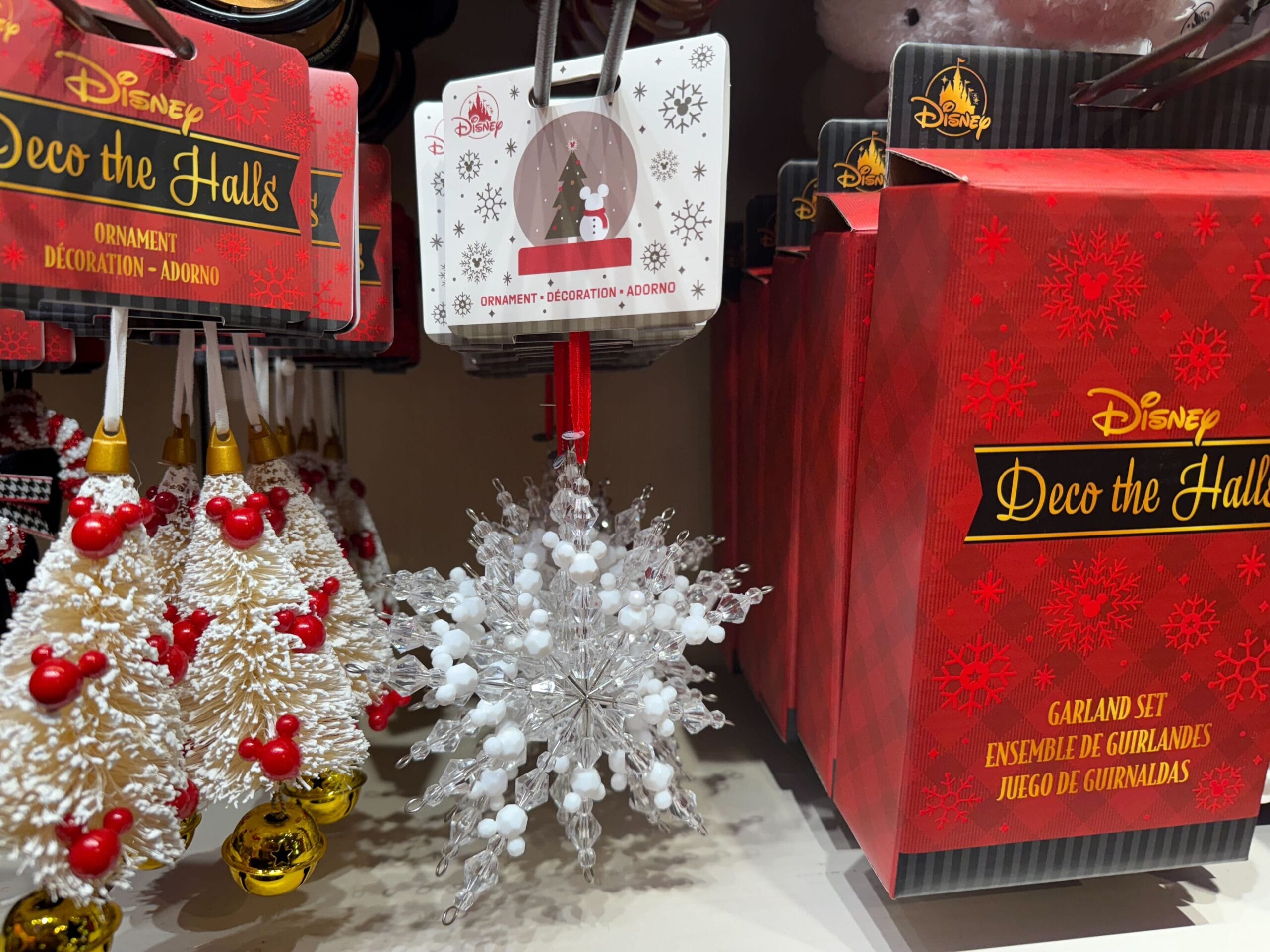 Disneyland Resort Christmas merchandise displays festive ornaments and garlands, with a white snowflake ornament—not WDW's castle.