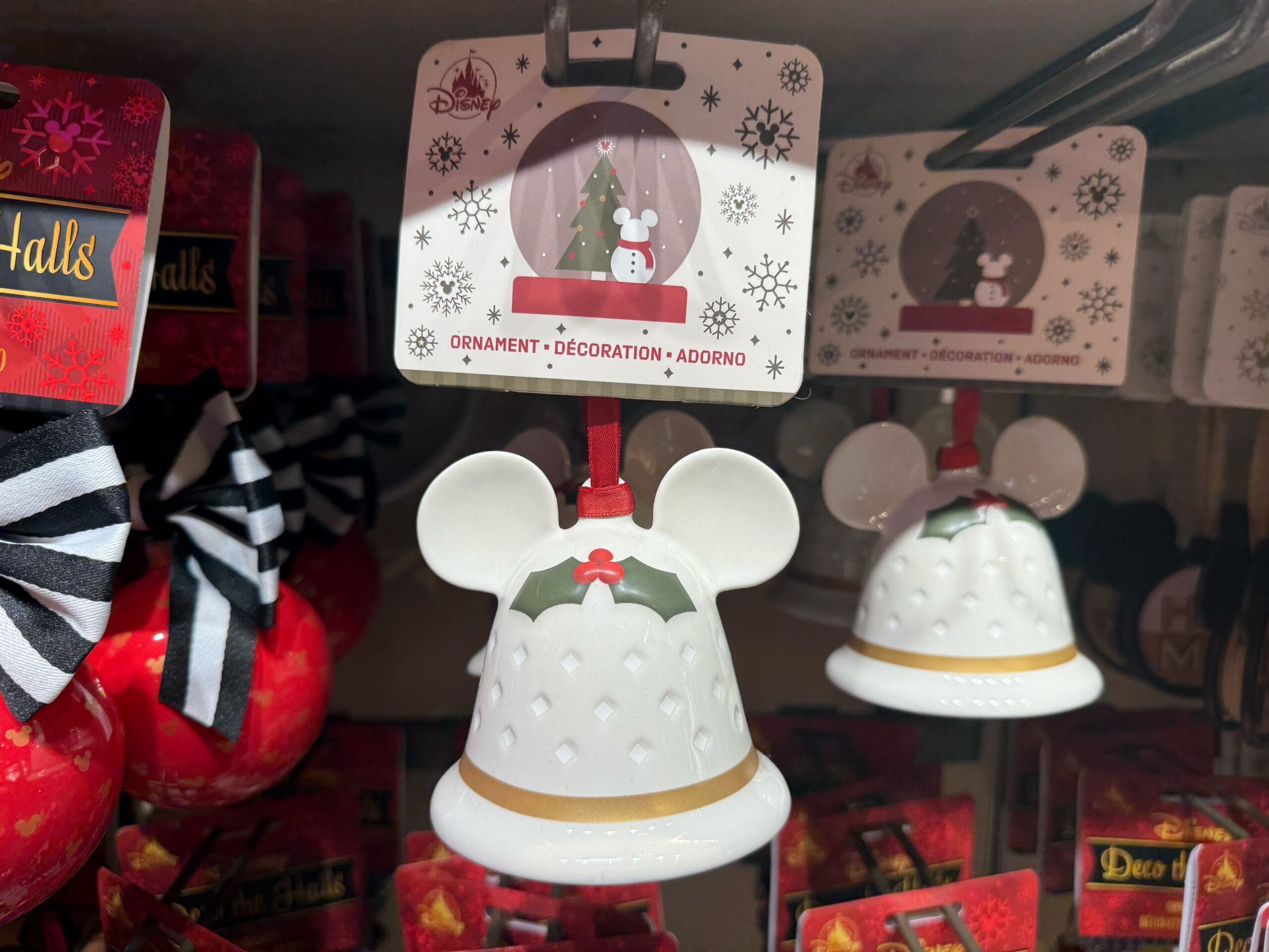White Mickey Mouse bell-shaped ornament with holly, sold as Christmas merchandise at Disneyland Resort—no castle pictured here.