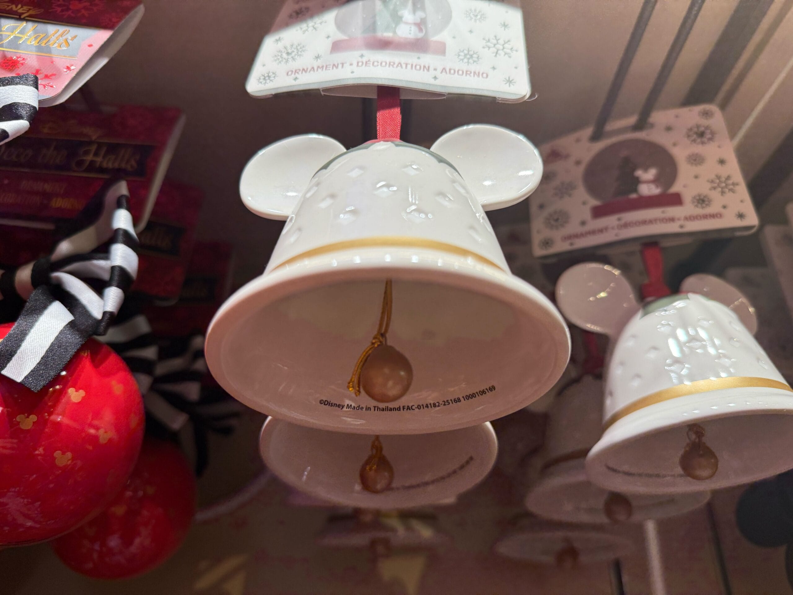 White ceramic Mickey Mouse ear bell ornaments with red ribbons on display at Disneyland Resort, reminiscent of magical park décor.