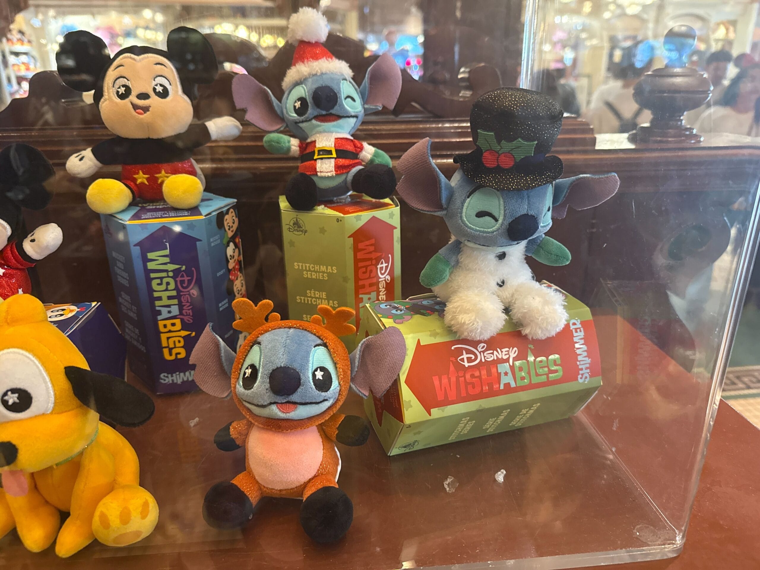 Festive Stitch and Disney plush toys in holiday outfits on Disney Wishables boxes, exclusive to Disneyland Resort, no castle shown.