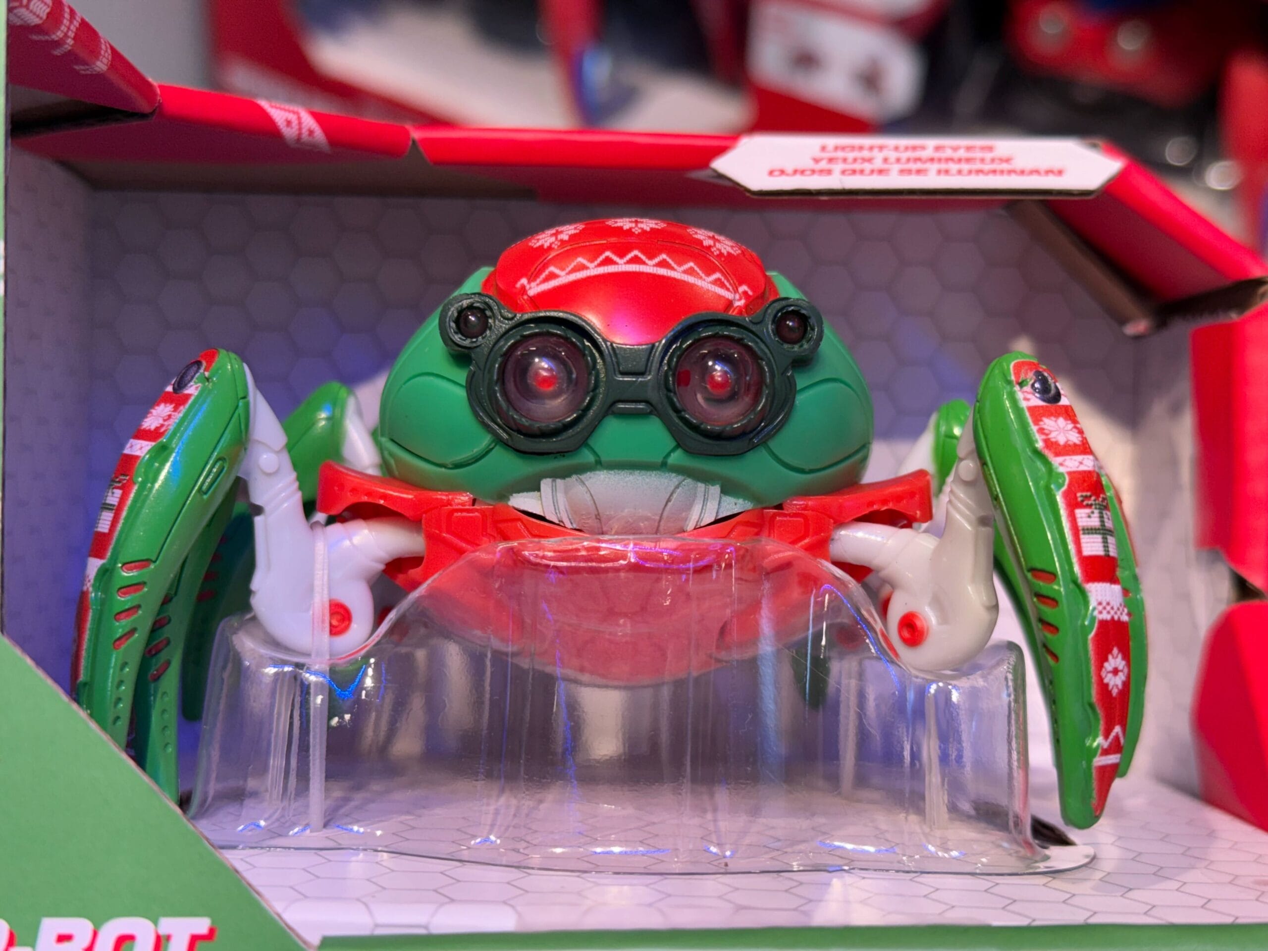 Christmas Spider-Bot toy with red and green legs, big eyes, and festive shell in a display box at Disneyland, not WDW.