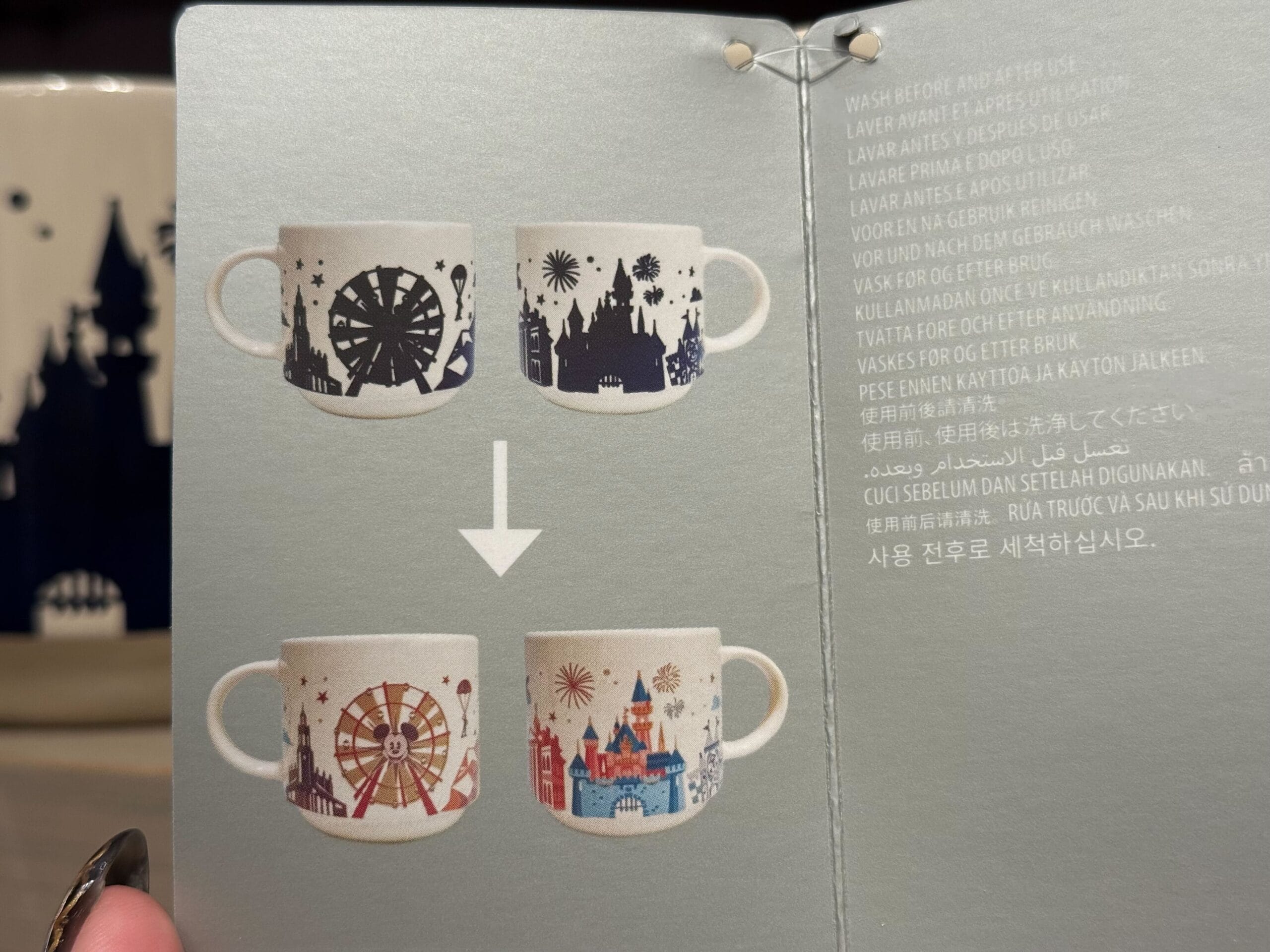 Two white mugs, once bearing black designs, burst into color with a ferris wheel, fireworks, and castles resembling Disney park icons.
