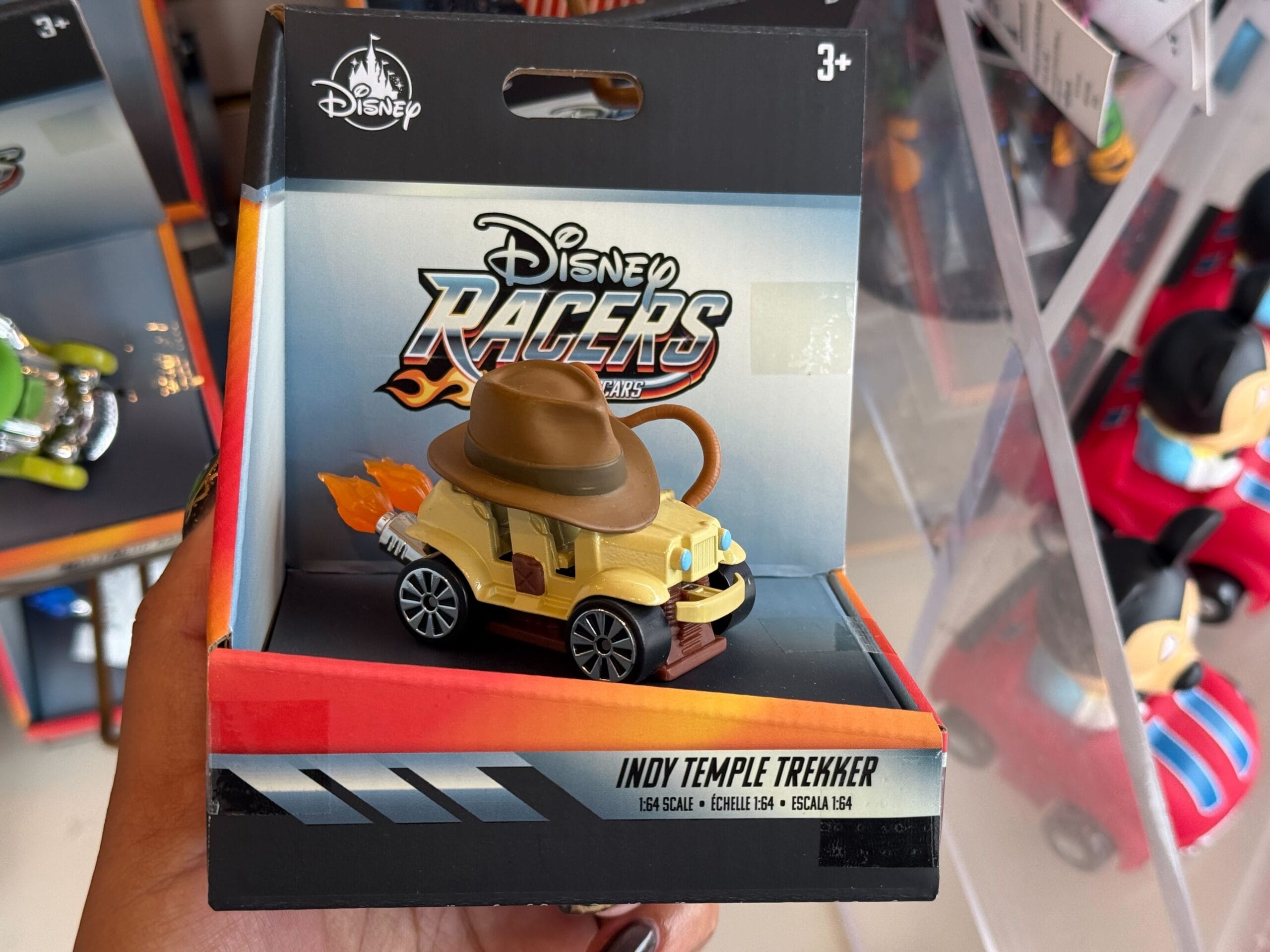 A Disney Racers Indiana Jones toy car with whip and fedora, "Indy Temple Trekker" in adventure packaging, like park collectibles.