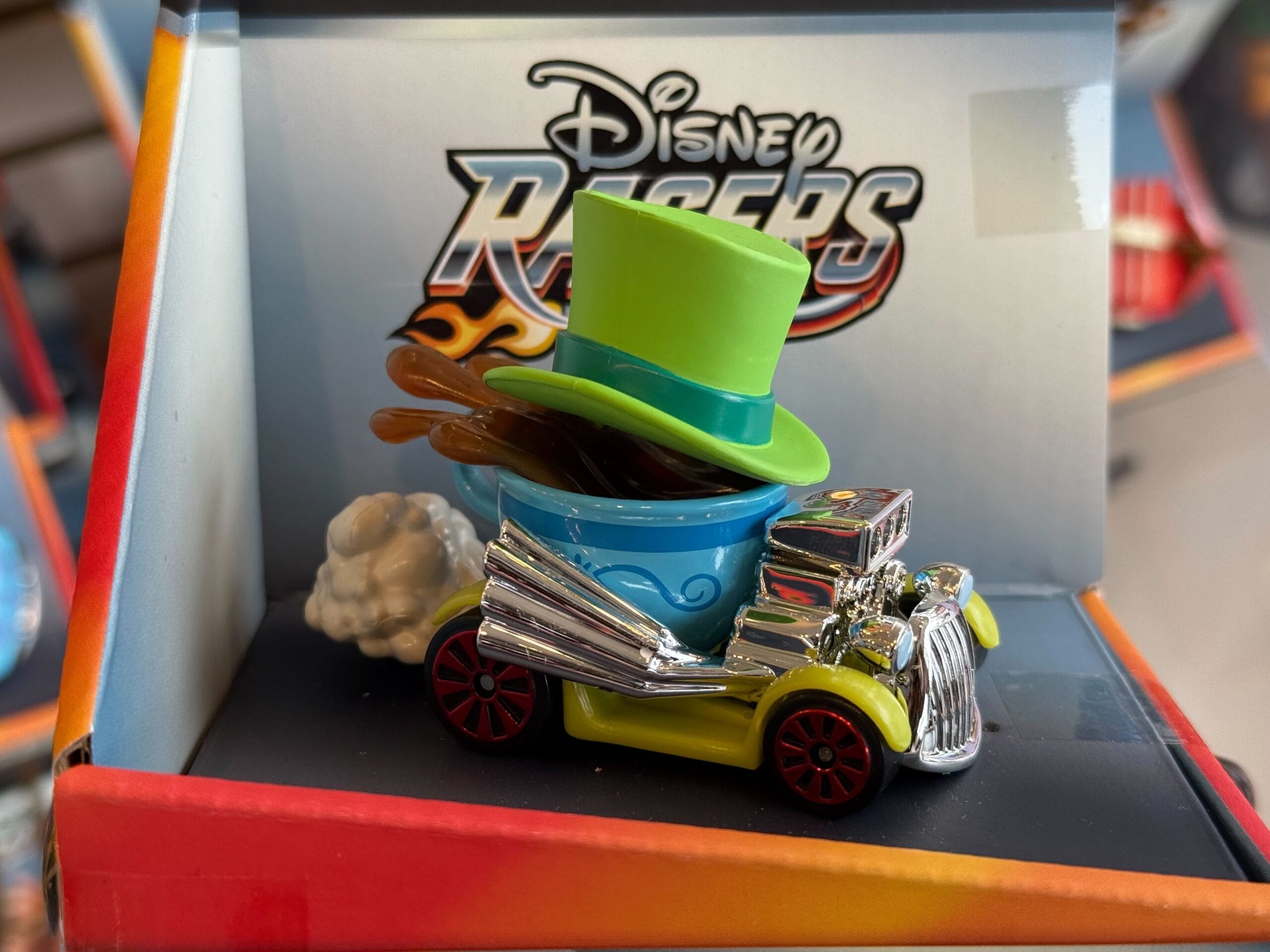 A Disney Racers toy car with a green hat and blue cup, displayed on a shelf, similar to collectibles found at Disney Parks.
