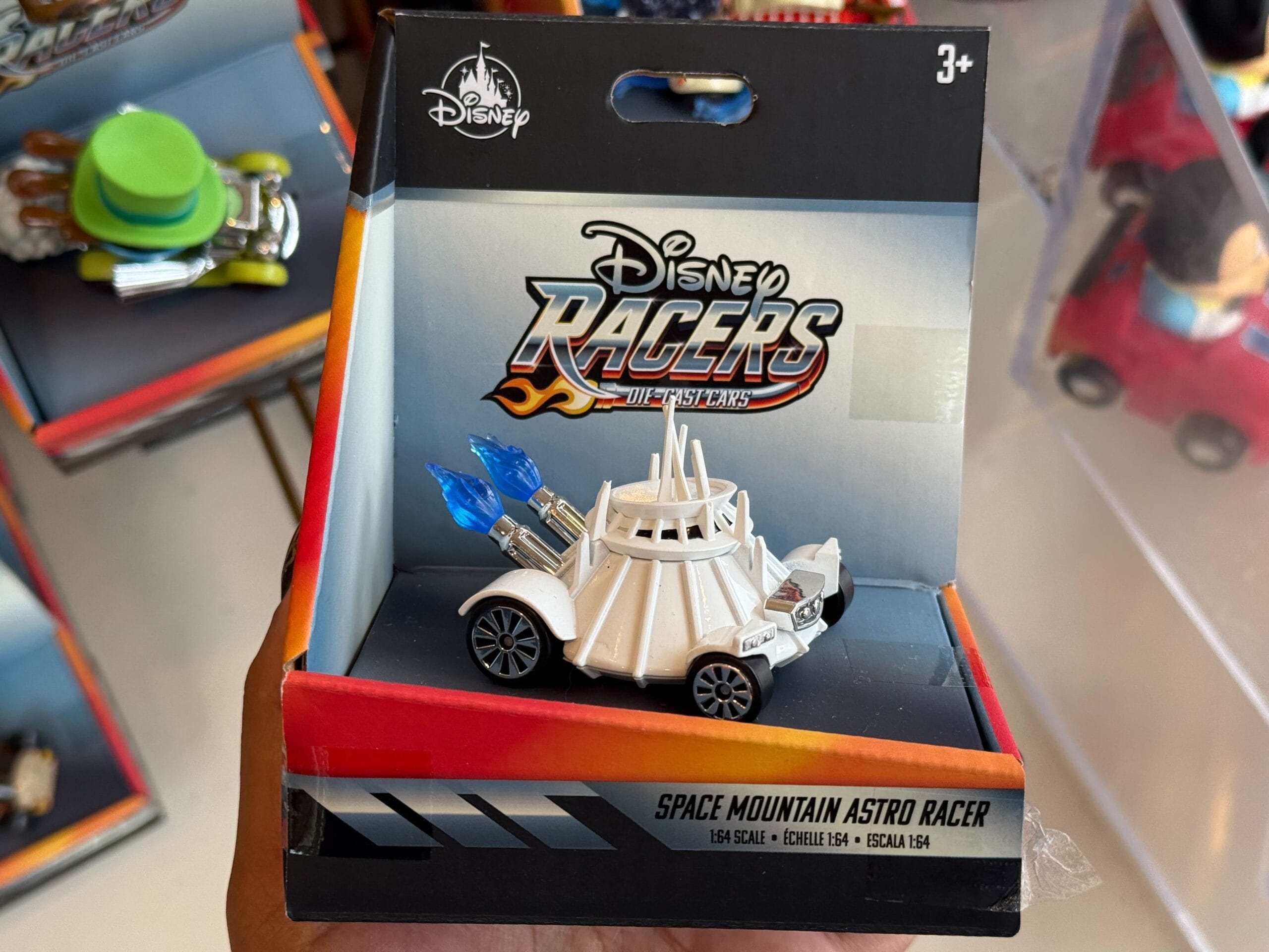 A Disney Racers Space Mountain car toy, white with blue rockets, packaged and displayed at Disneyland, home to the original castle.