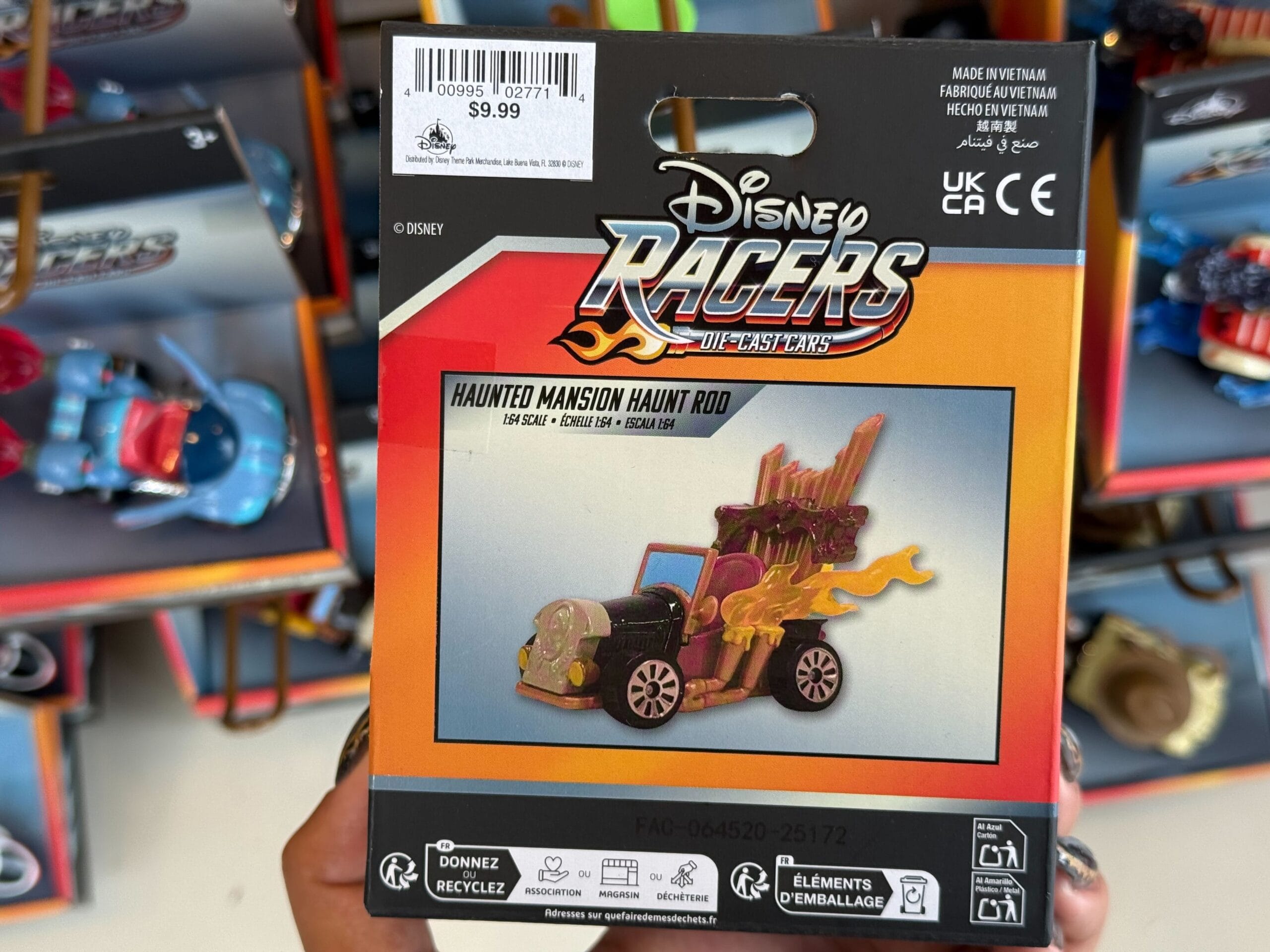 A Disney Racers Haunted Mansion racecar toy in its package is held up at Disneyland, price tag $9.99 visible, no castle shown.