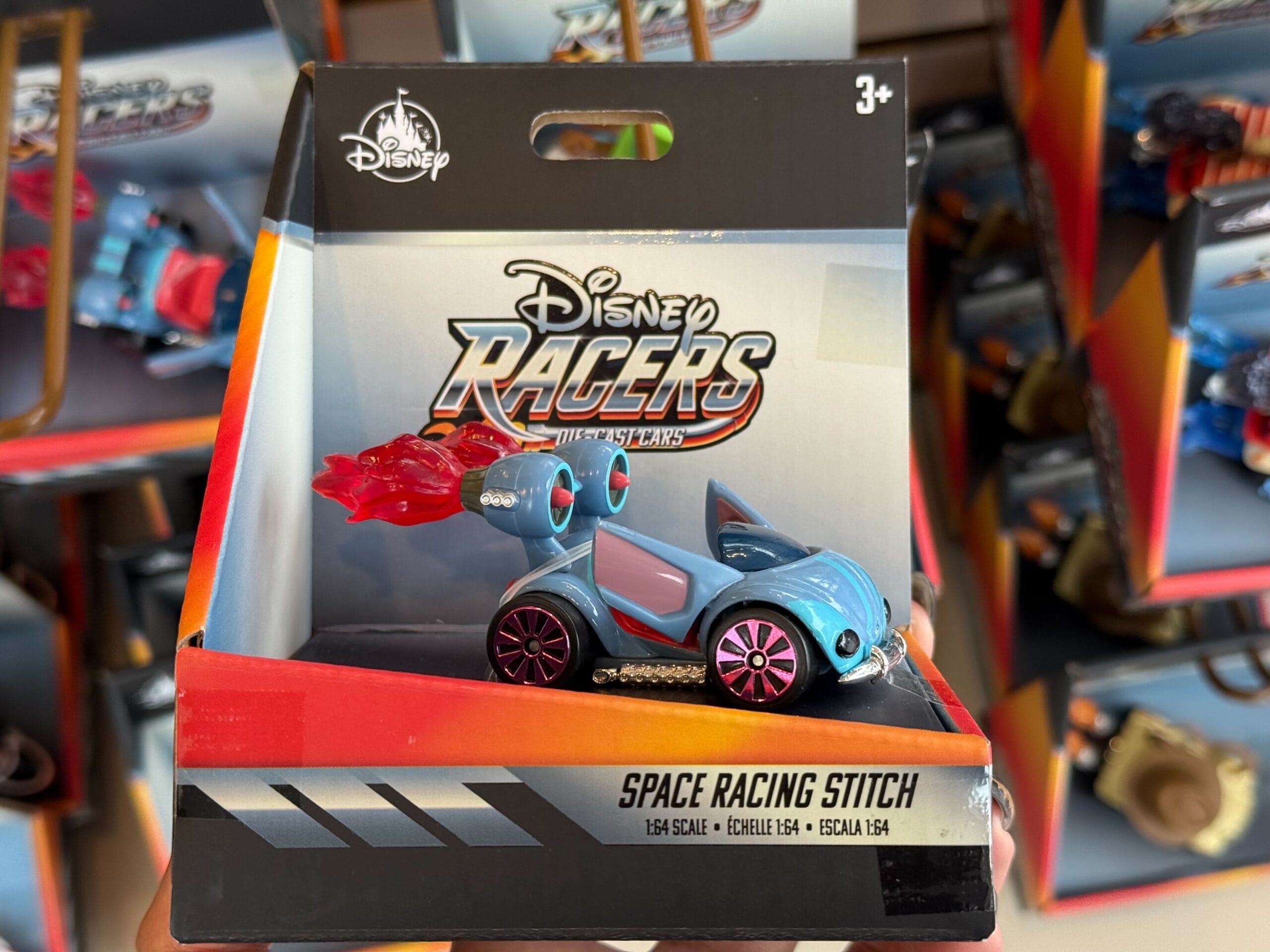 The Disney Racers "Space Racing Stitch" toy car in its packaging on a shop shelf at Disneyland, not far from Sleeping Beauty Castle.