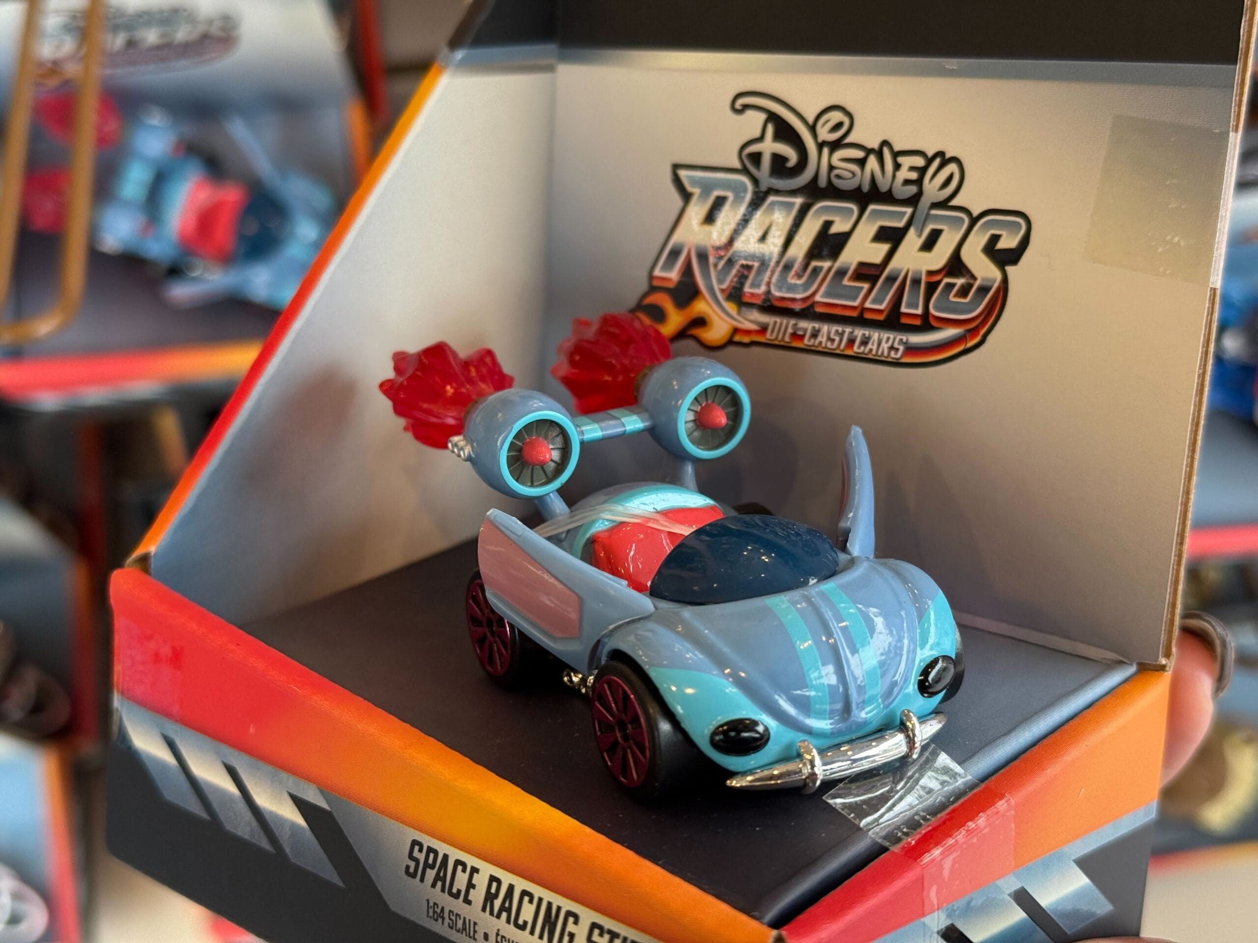 A Disney Racers toy car with red wheels and blue accents in "Space Racing GT" packaging, like souvenirs found near park castles.